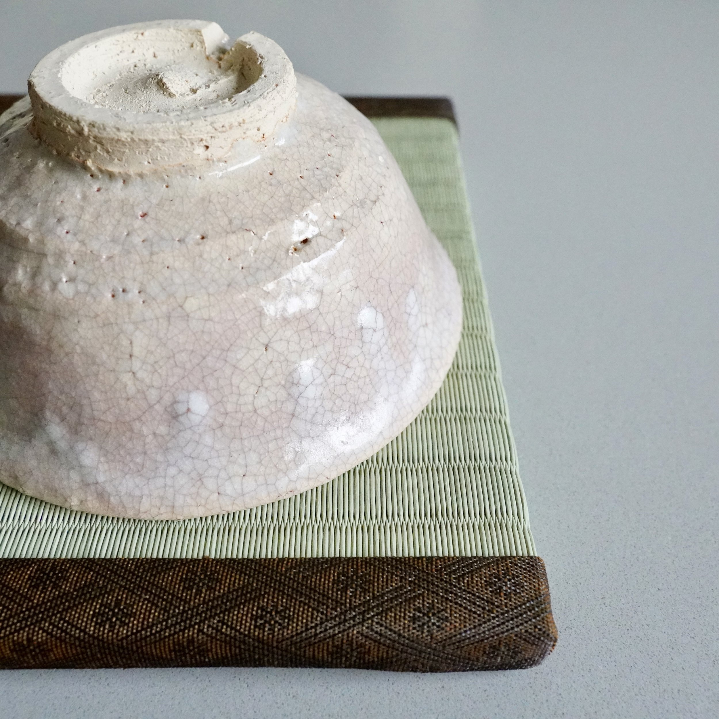Hagi-yaki chawan tilted to show kirikōdai foot ring and clay body texture at the base