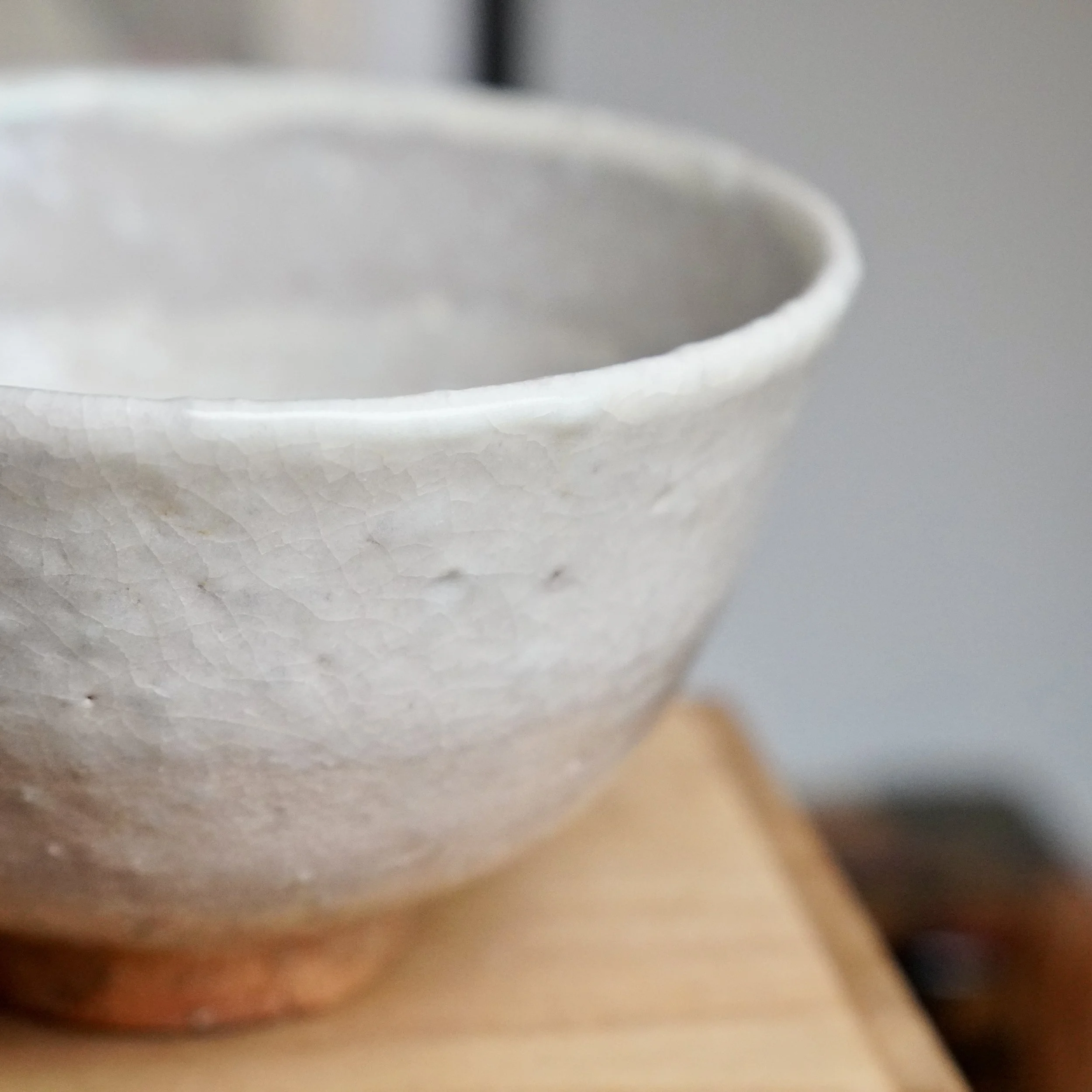 Tamamura Shōgetsu's Hagi-yaki chawan, angled view of its crackled off-white glaze with tea stains, fading to reddish clay at the base.
