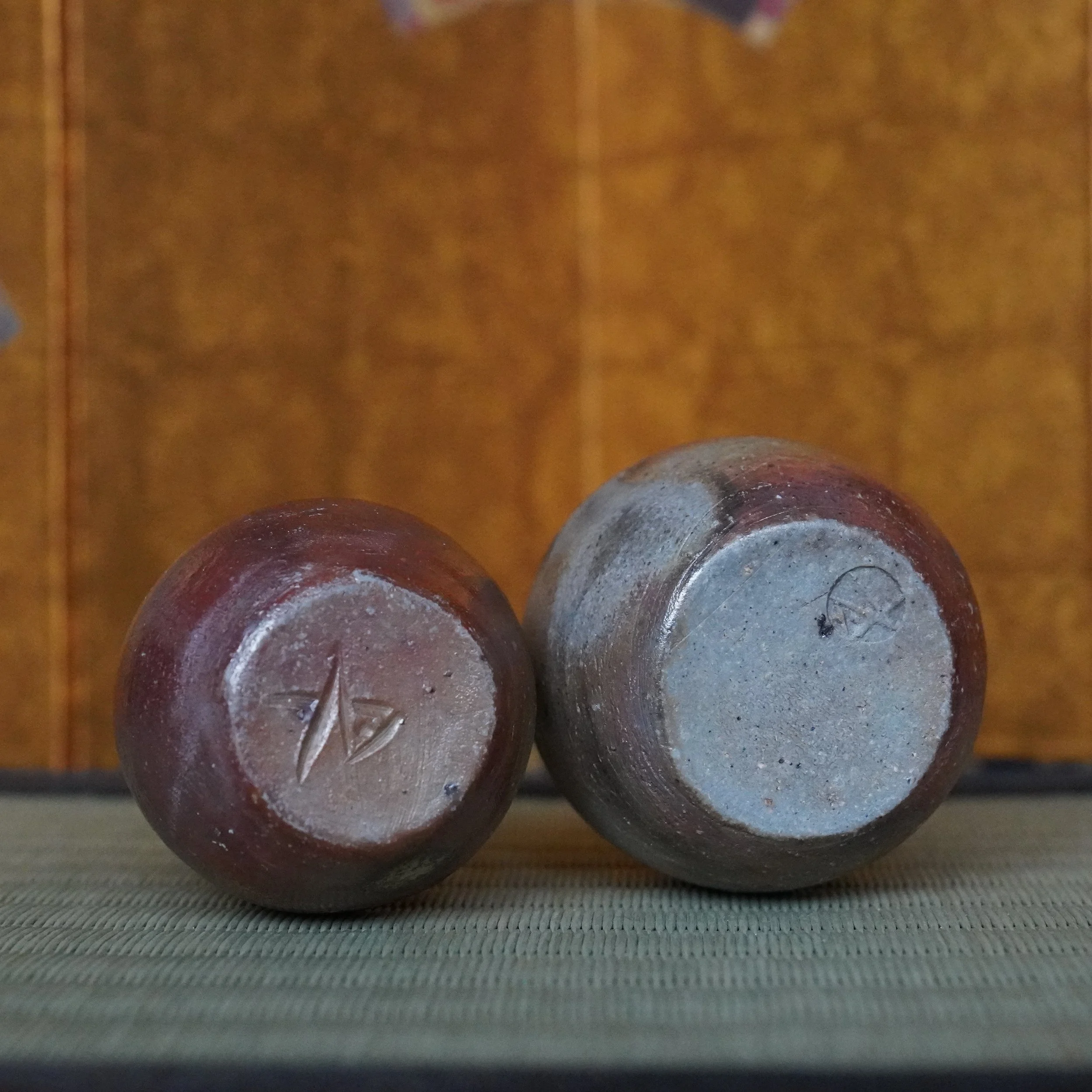 Undersides of two Bizen-yaki vases by Shibaoka Tōsendō. One with carved mark and the other with stamp on the bottom.