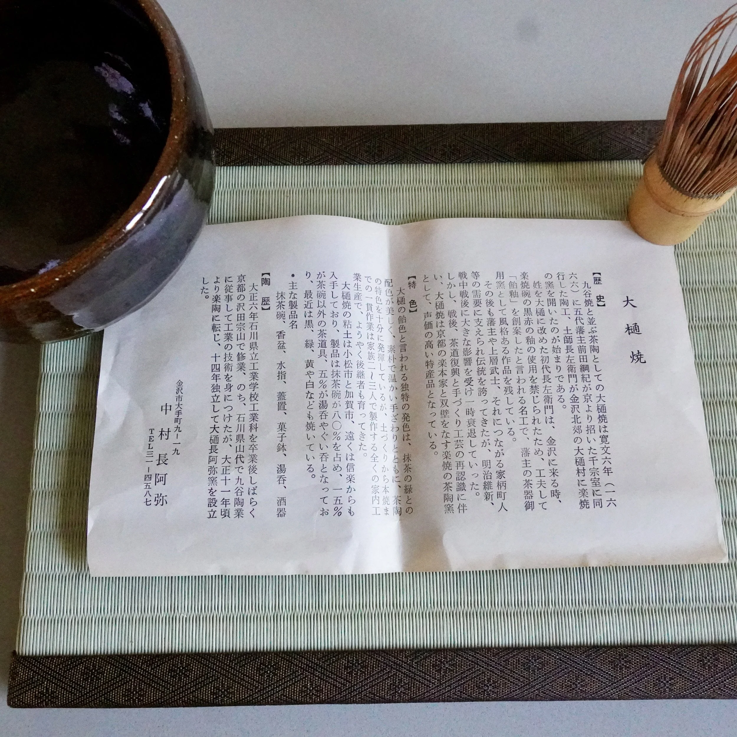 Ōbi-yaki chawan by Nakamura Chōami resting beside its original atelier leaflet on a tatami mat