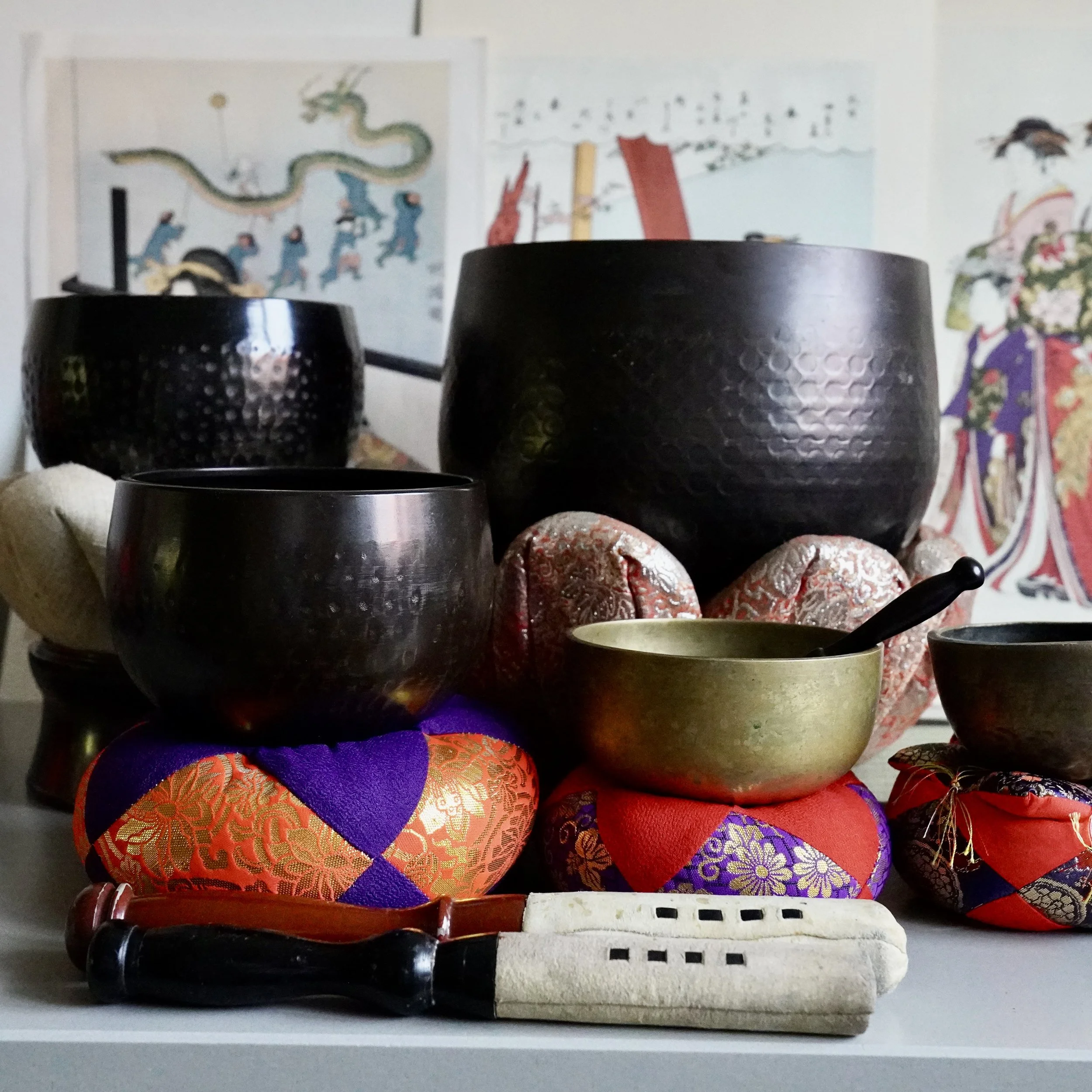 Vintage Japanese orin singing bowls of different sizes, including a large signed Tsutsumi orin, on brocade cushions