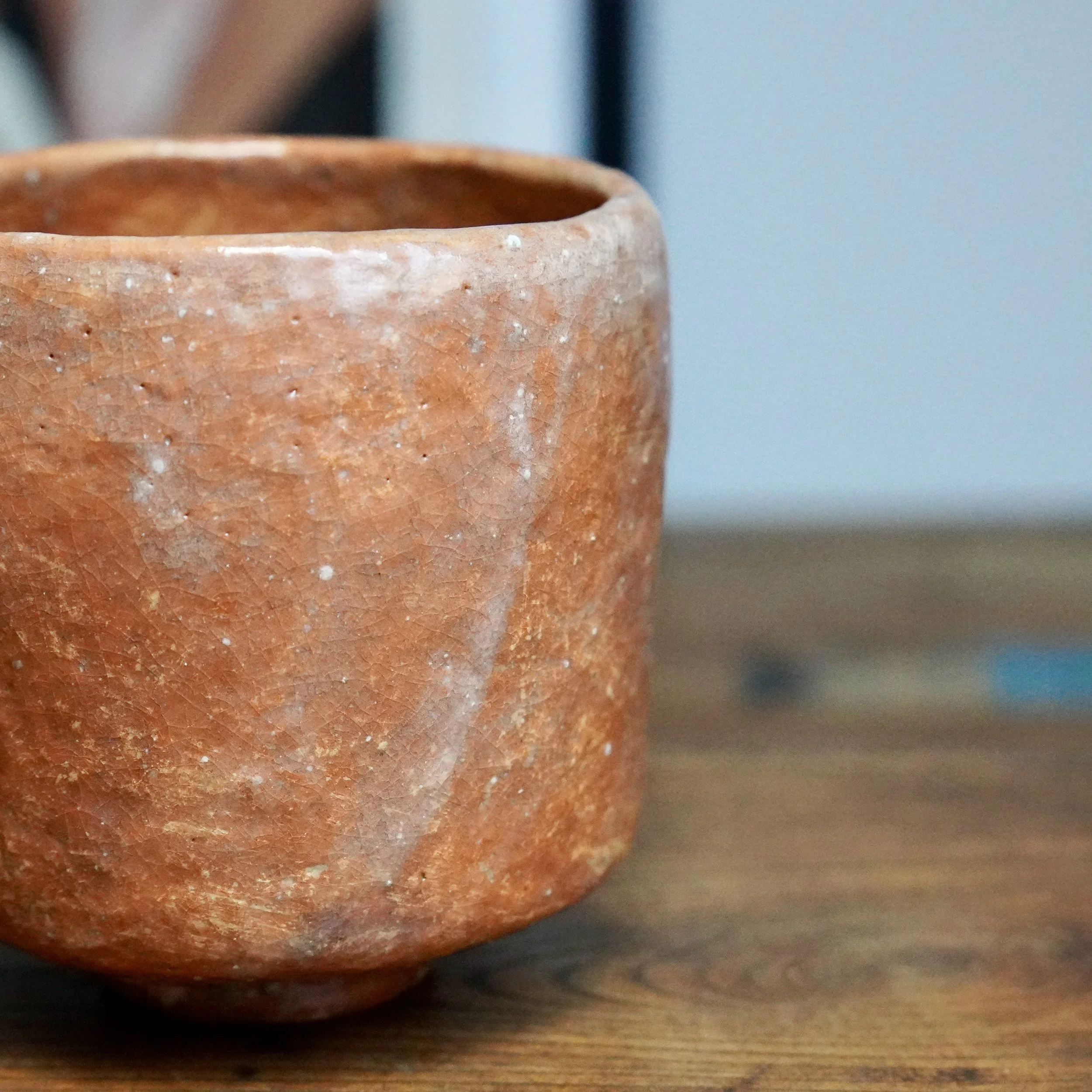 Terracotta tsutsu chawan by Hioki Nanshū kiln, showing crackle glaze and white drips, close-up.
