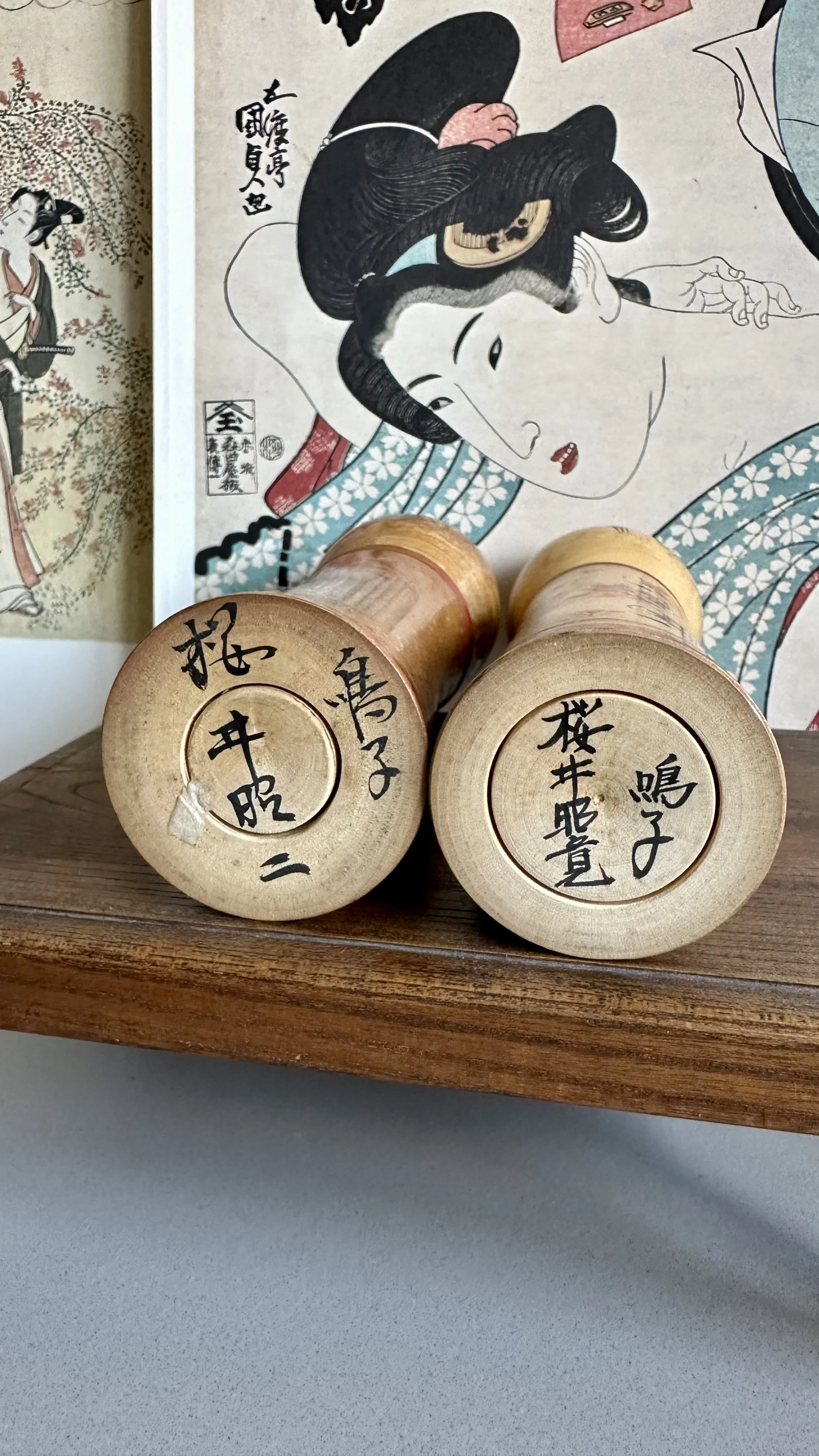 Signed bases of two Naruko kokeshi by Sakurai Shoji (桜井昭二) and Sakurai Akihiro (桜井昭寛) showing family signatures and Naruko tradition mark side by side