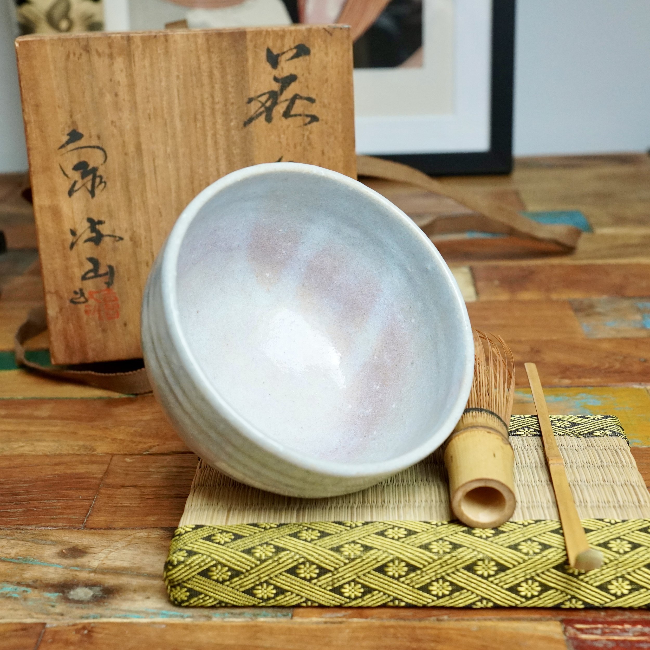 Iridescent white Hagi-yaki chawan with hints of lilac, a bamboo whisk, scoop, and patterned mat, with a signed tomobako box by Moriwaki Fumitada.