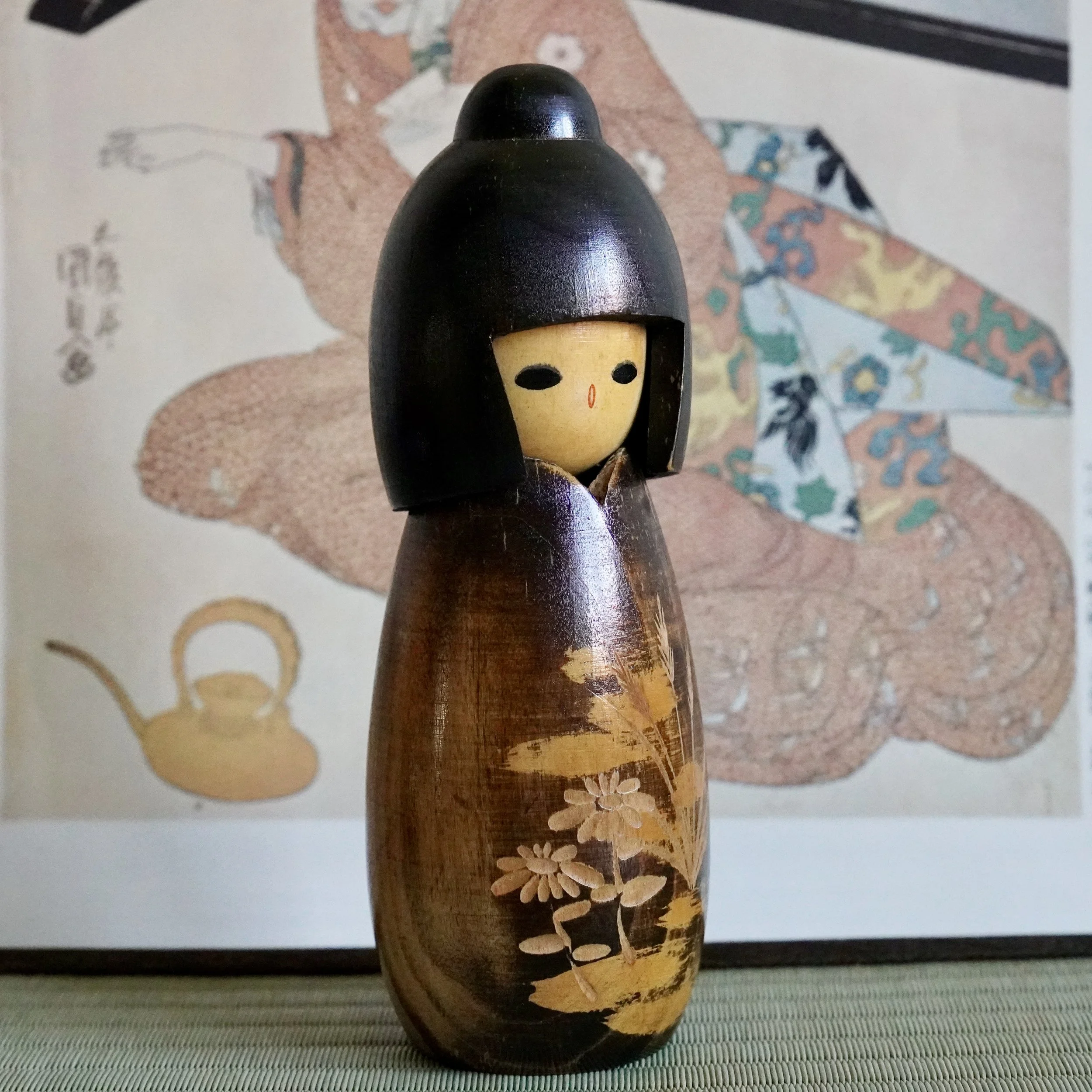 Sōsaku kokeshi three-quarter view showing carved grasses and face