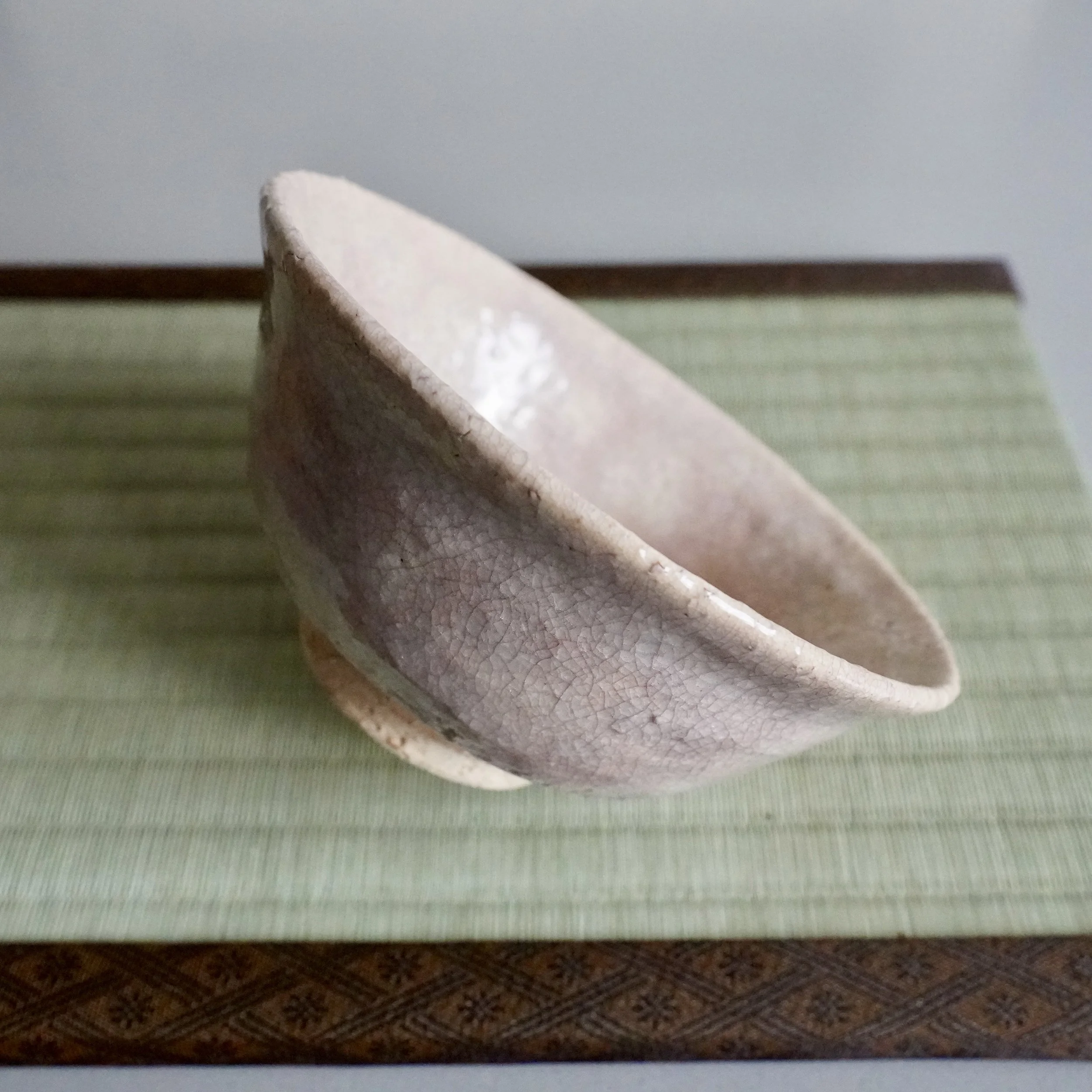 Hagi ware chawan tilted at angle, showing full crackled glaze surface and wide summer bowl form