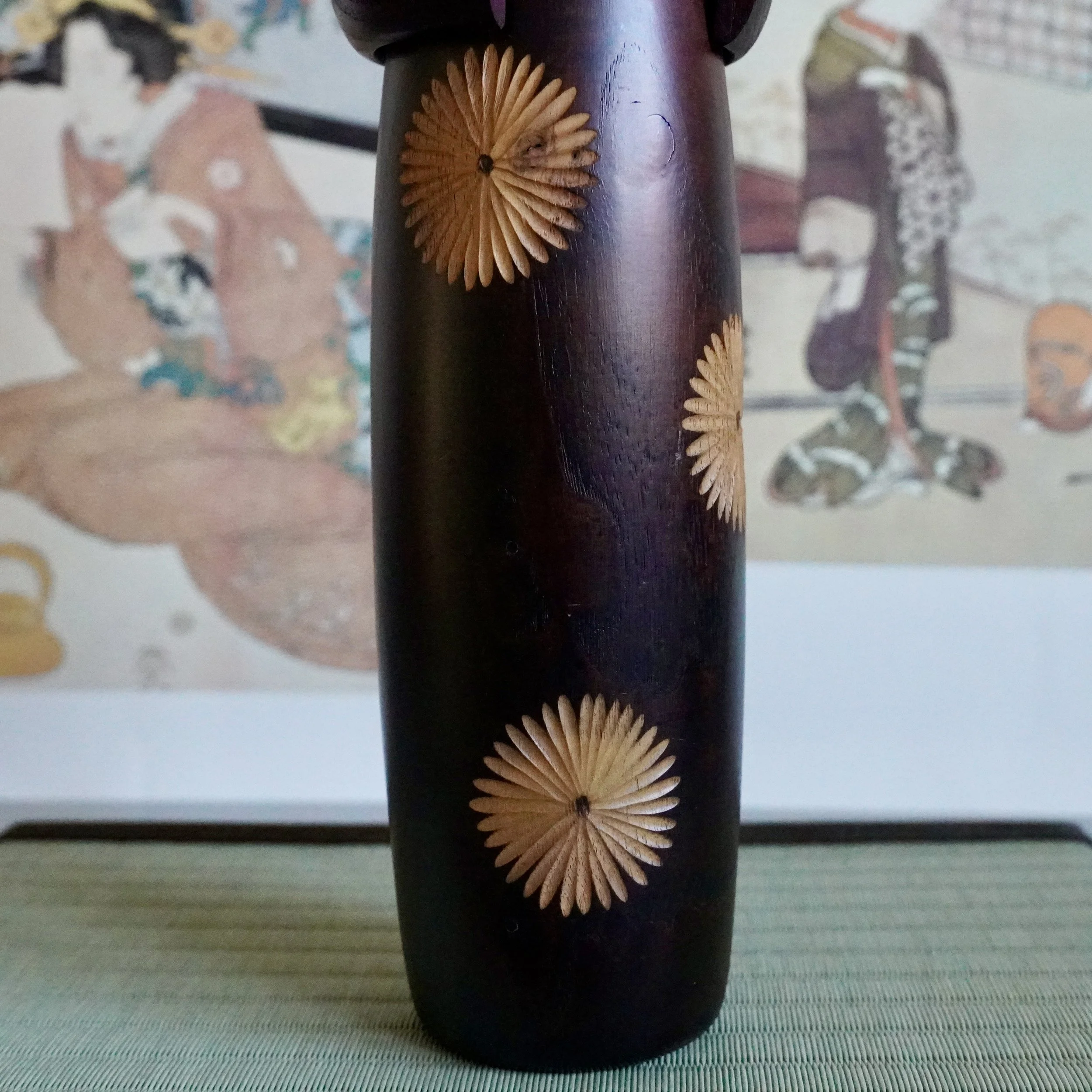 Usaburo kokeshi front view, chrysanthemum inlay pair on dark wood, downcast face, Gunma Japan