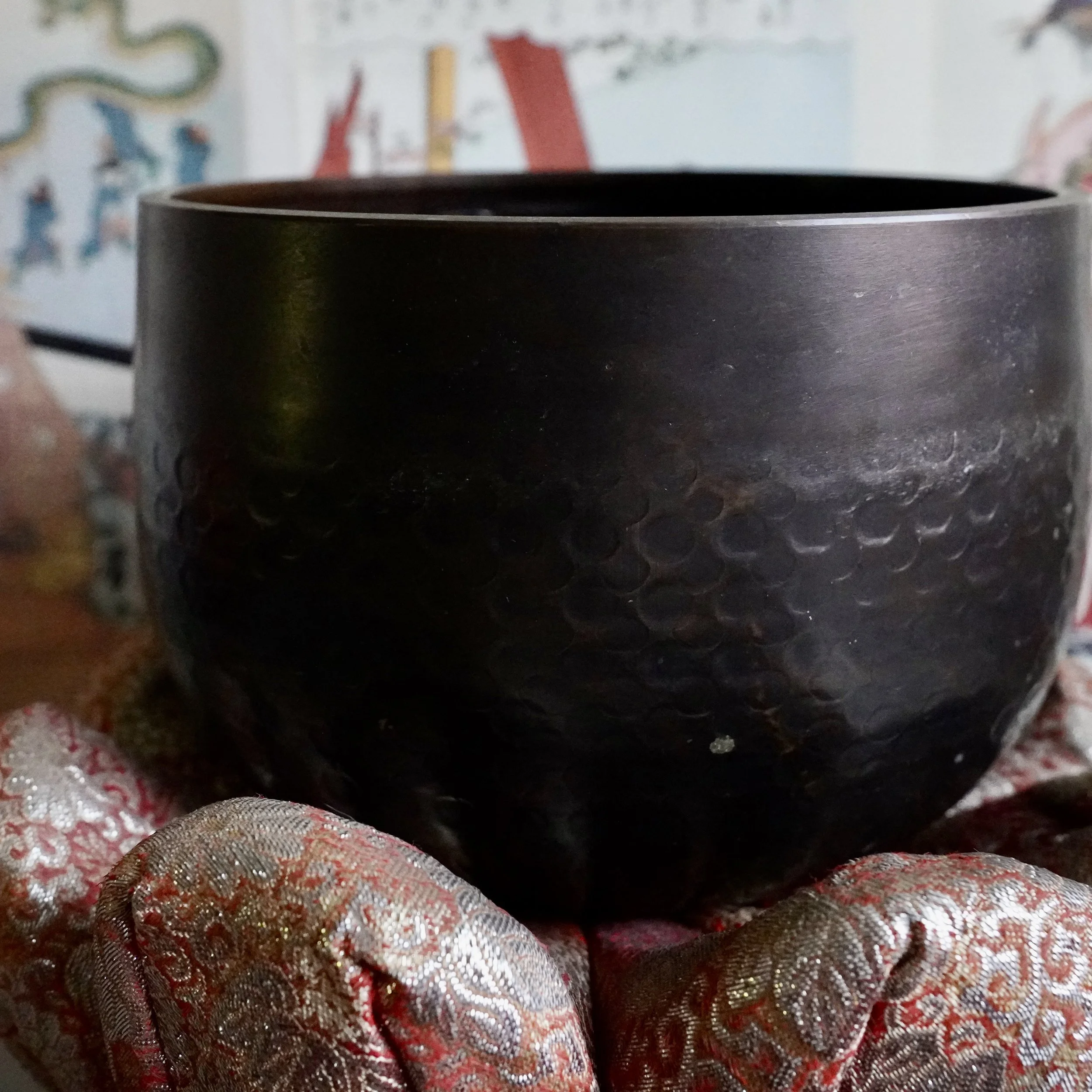Front view of large signed Tsutsumi orin, Japanese bronze singing bowl, on brocade cushion