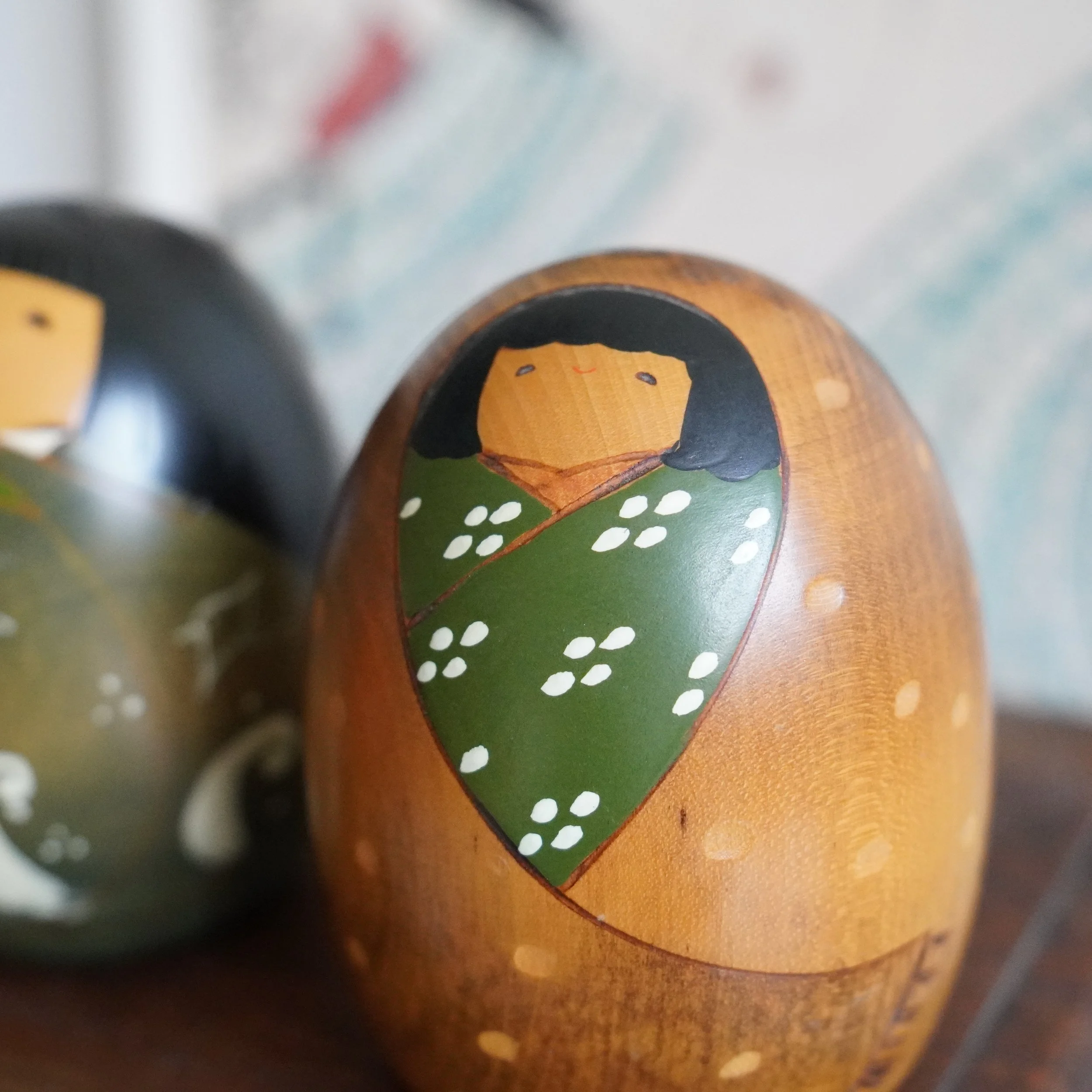 Close up of vintage Usaburo kokeshi pair, egg shaped sosaku kokeshi, summer and winter design, Showa period Japan