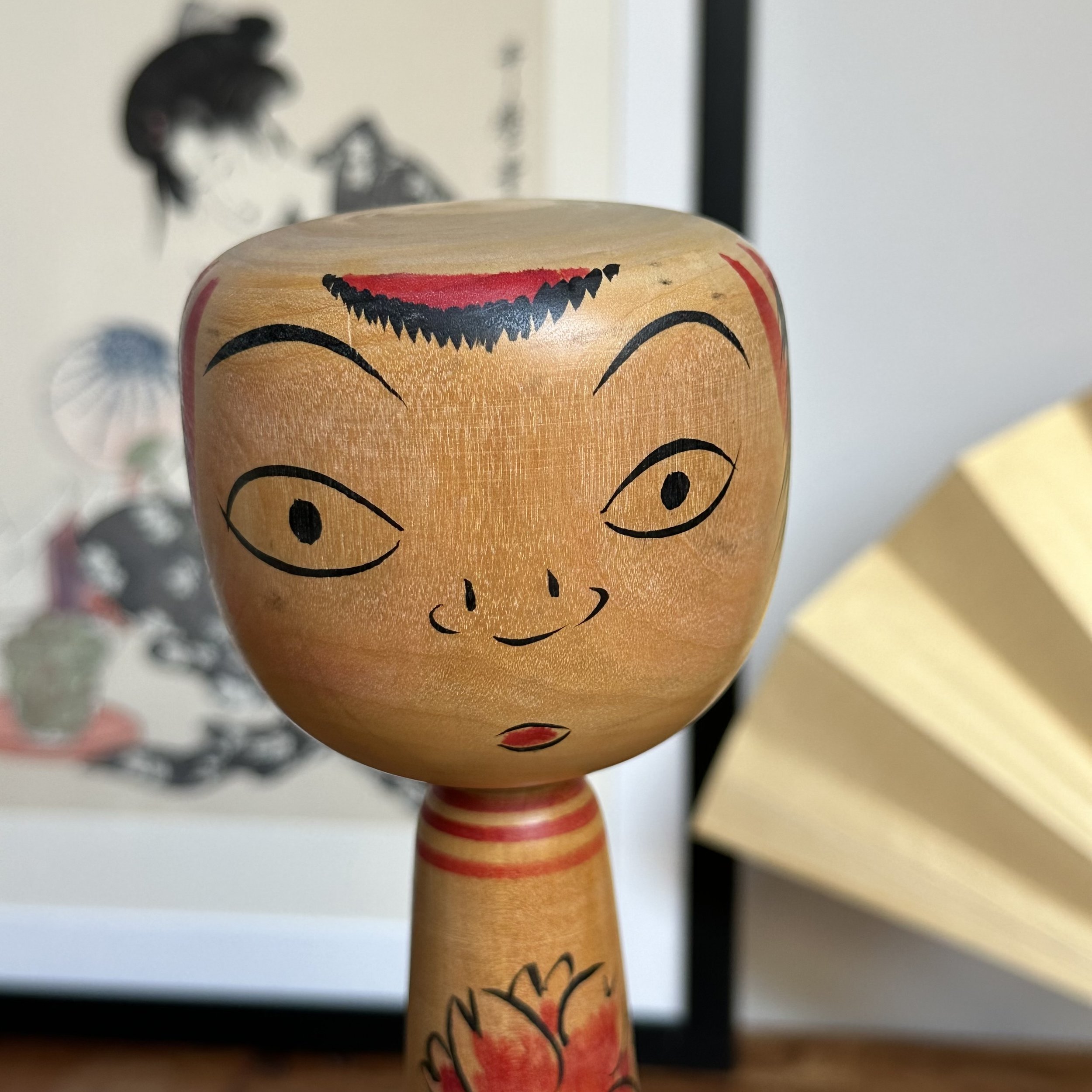 Seya Jūji Nakanosawa Takobozu kokeshi, front view. Light wood face with black eyes, a smile with red lips, and an expressive higher eyebrow.