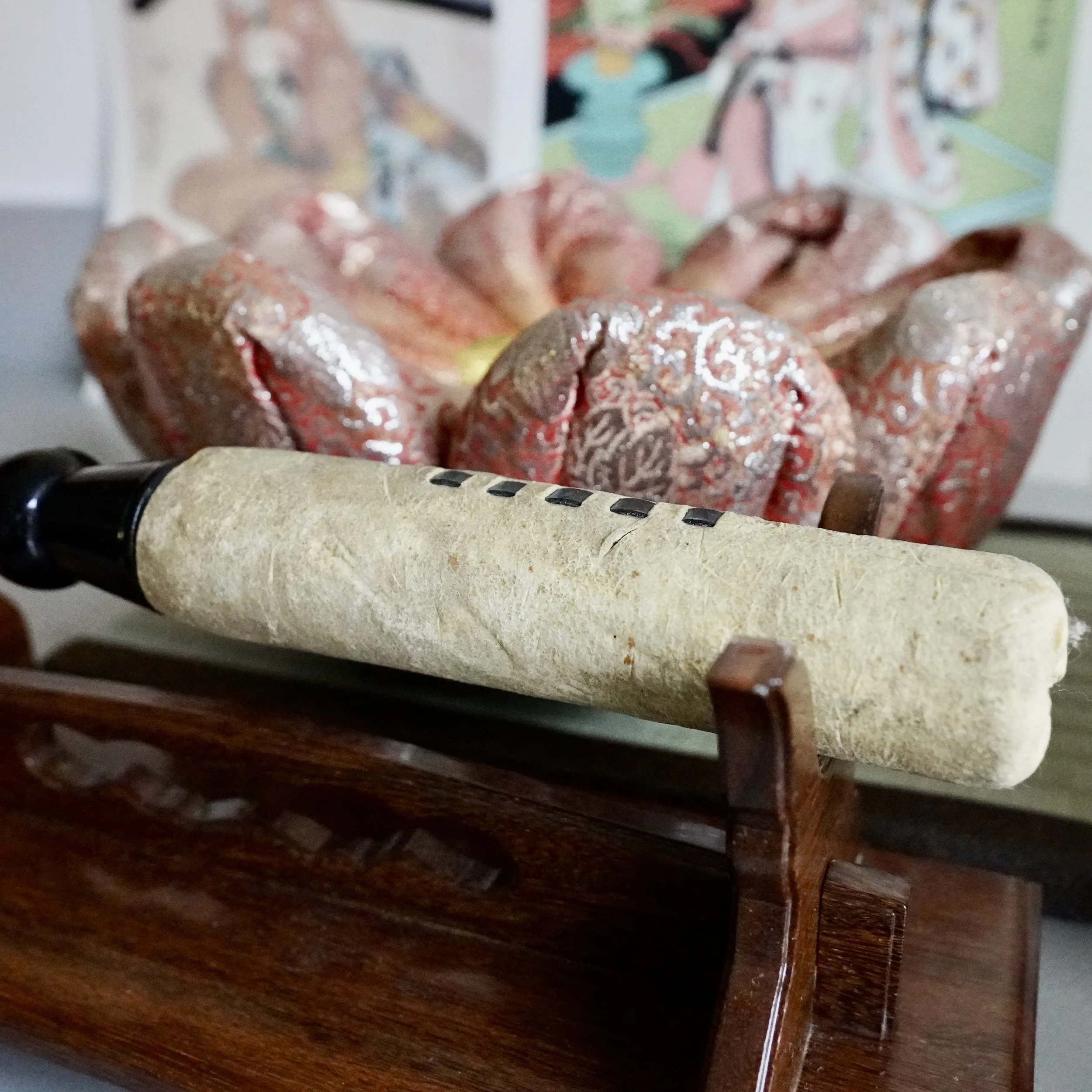 Brocade cushion with striker resting on wooden stand for Japanese orin singing bowl, angled view