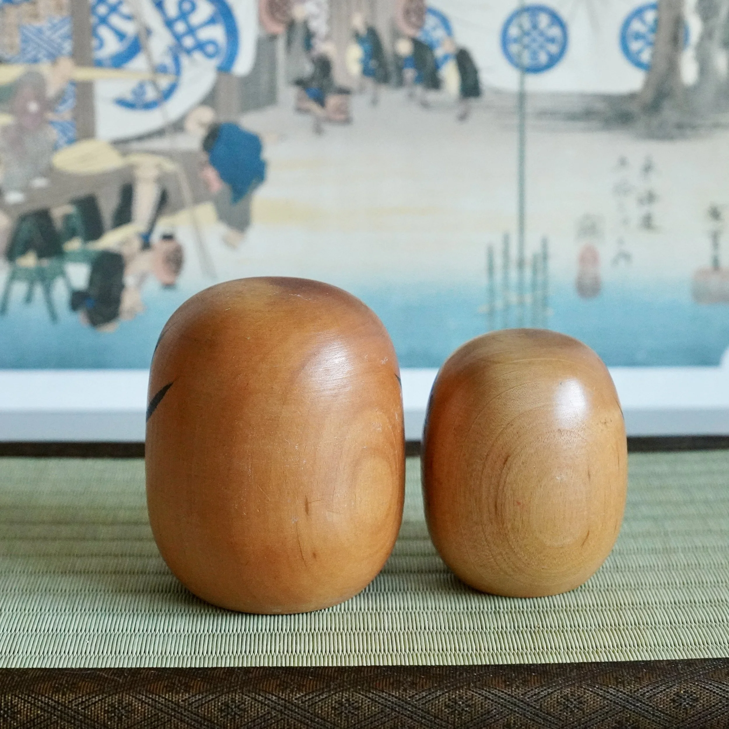 Back view of a vintage wooden daruma pair, plain turned wood grain, Tohoku kokeshi style craft.