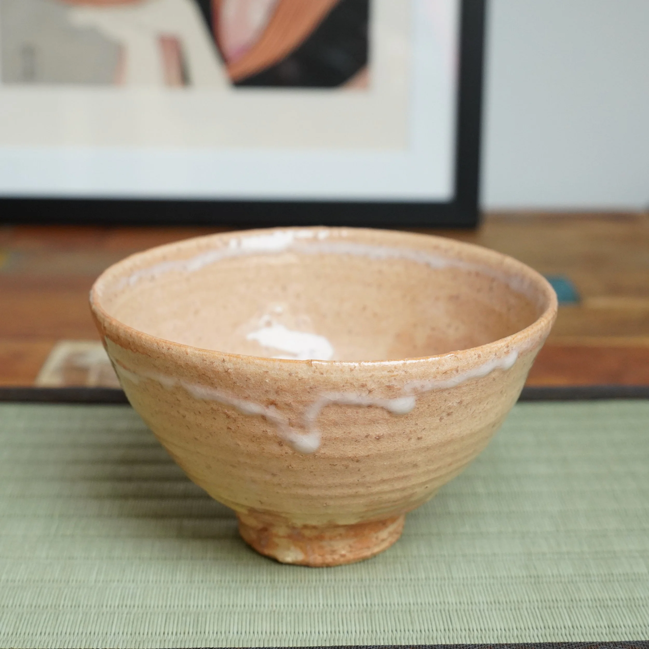 Kaneko Nobuhiko's Hagi-yaki chawan, salmon pink with visible wheel rings, crackled texture, and milky white glaze drips from the rim, on a tatami mat.