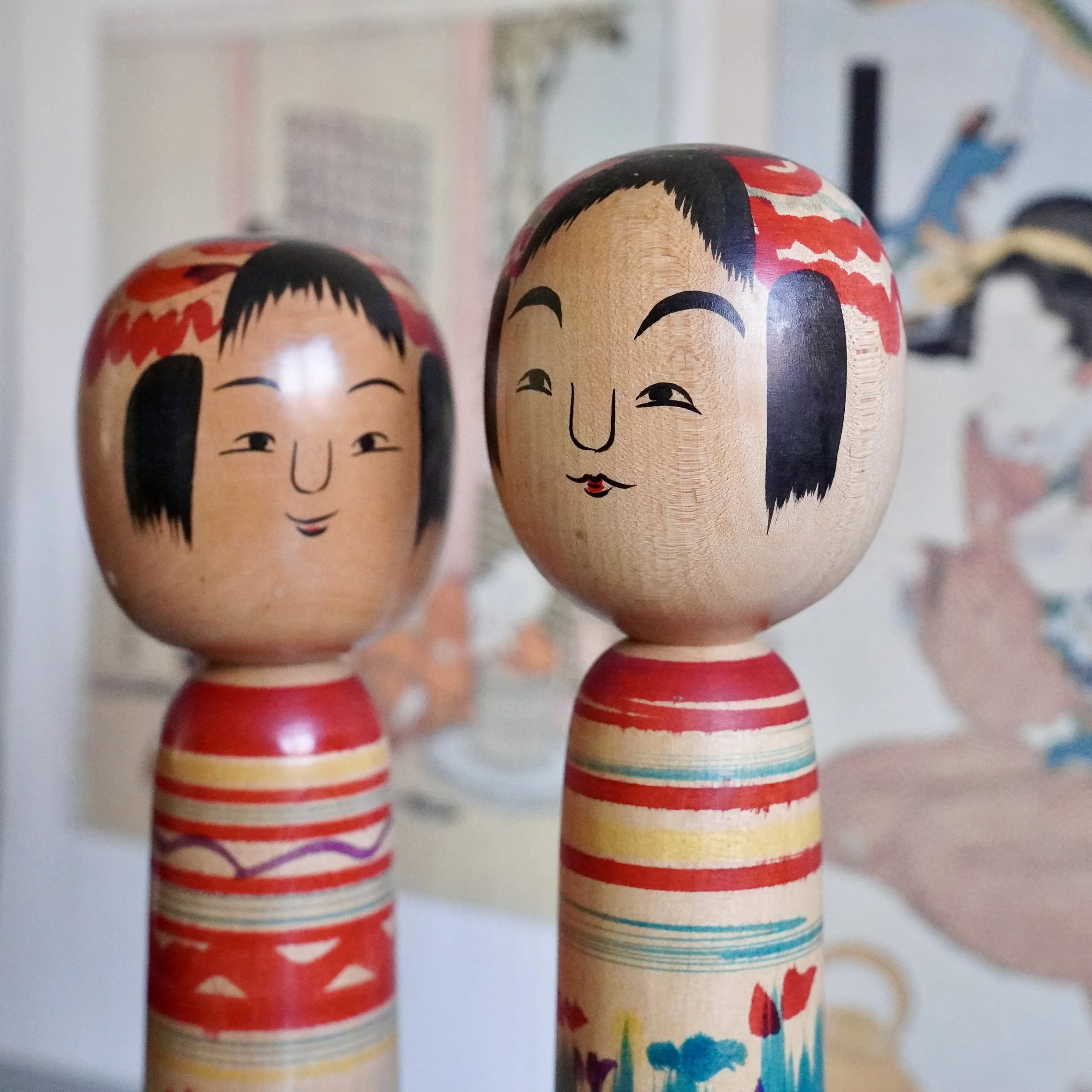 Close-up of two hand painted kokeshi doll faces, vintage Japanese Tsuchiyu craftsmanship.