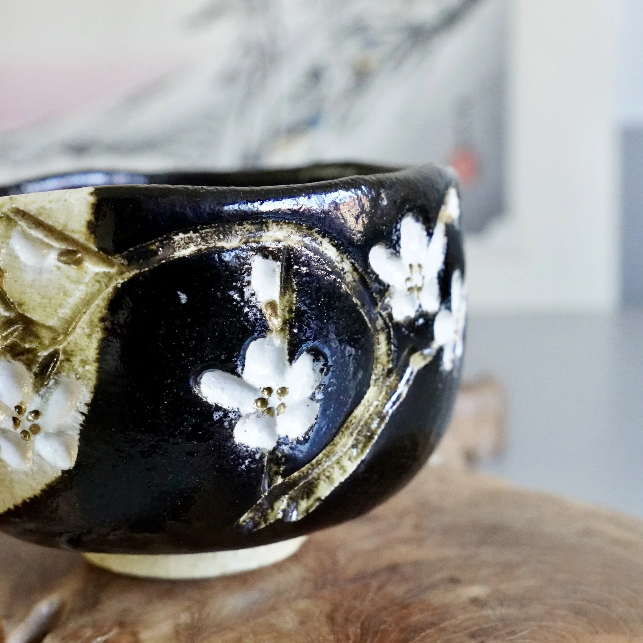Angled close-up of cherry blossom design on kuro chawan