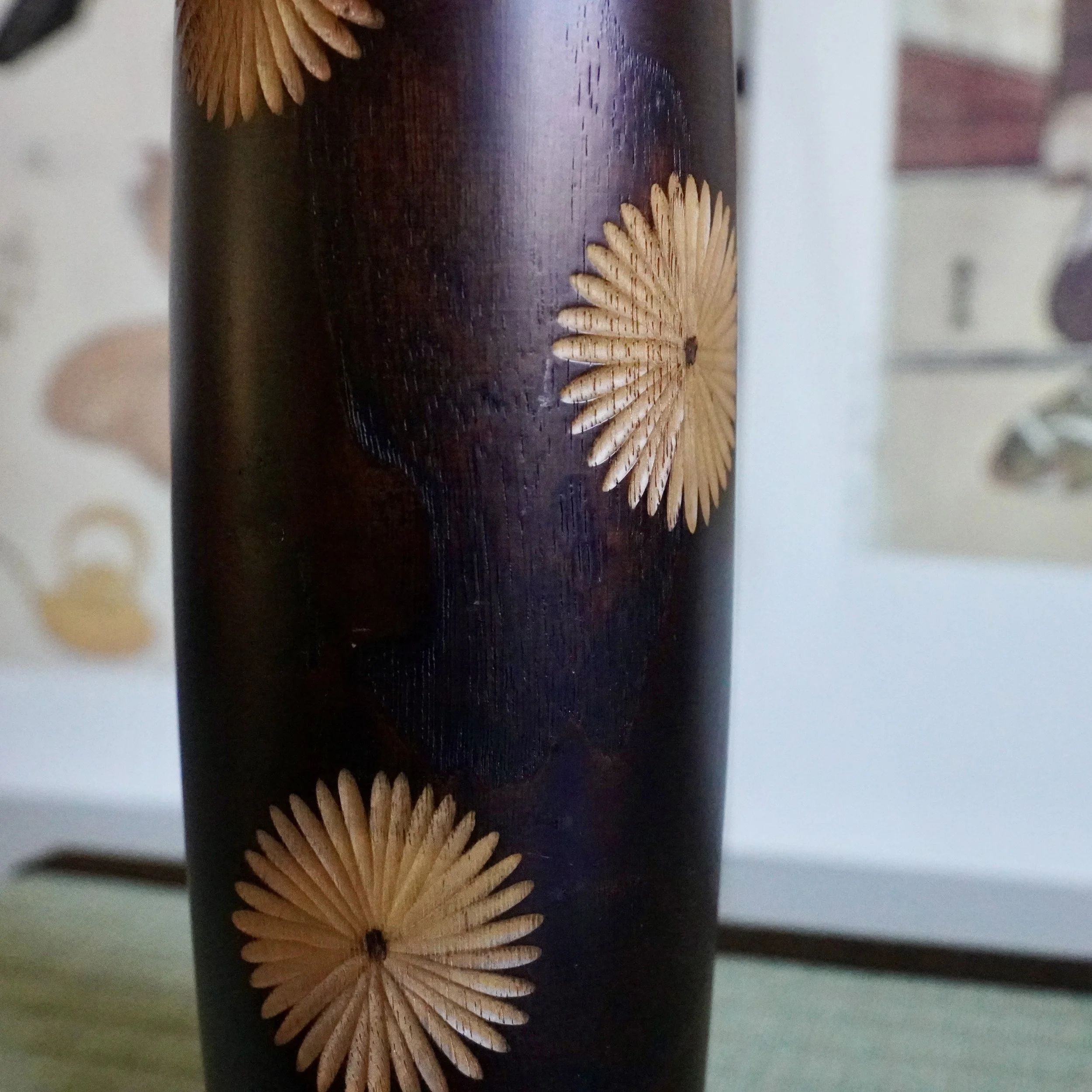 Chrysanthemum wood inlay close up on dark stained kokeshi body, Usaburo sosaku craftsmanship