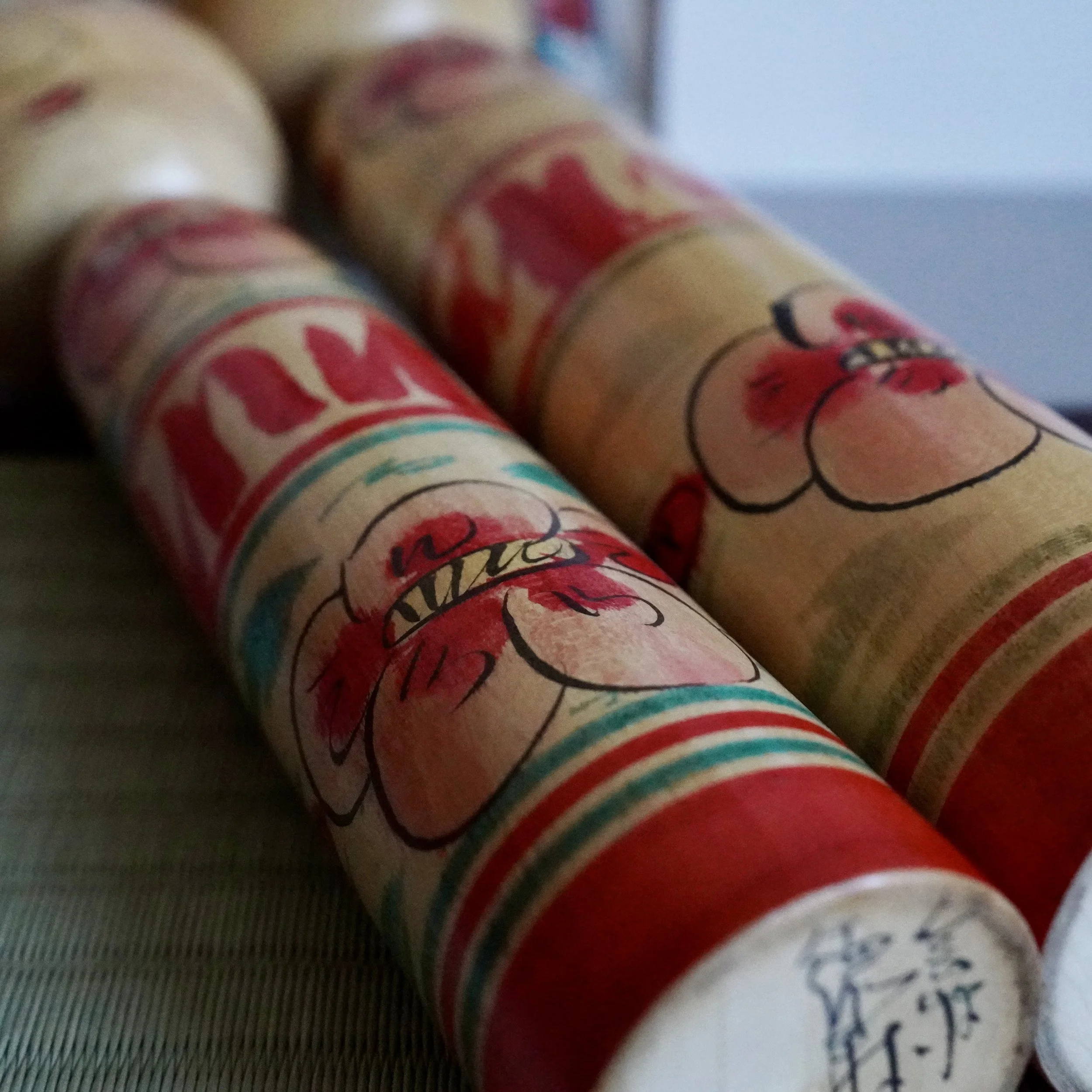 Nakanosawa Takobozu kokeshi lying on side showing signed base and hand painted peony detail, vintage Saito Tokuju kokeshi