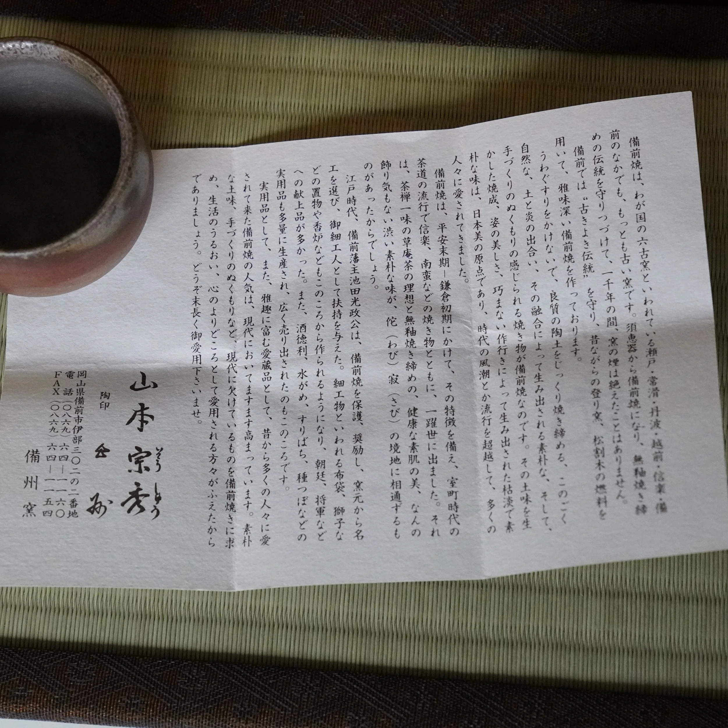 Bizen-yaki guinomi by Yamamoto Sōshū, reddish-brown with visible hidasuki marks, a dark interior, and uneven rim, placed on tatami next to a shiori.