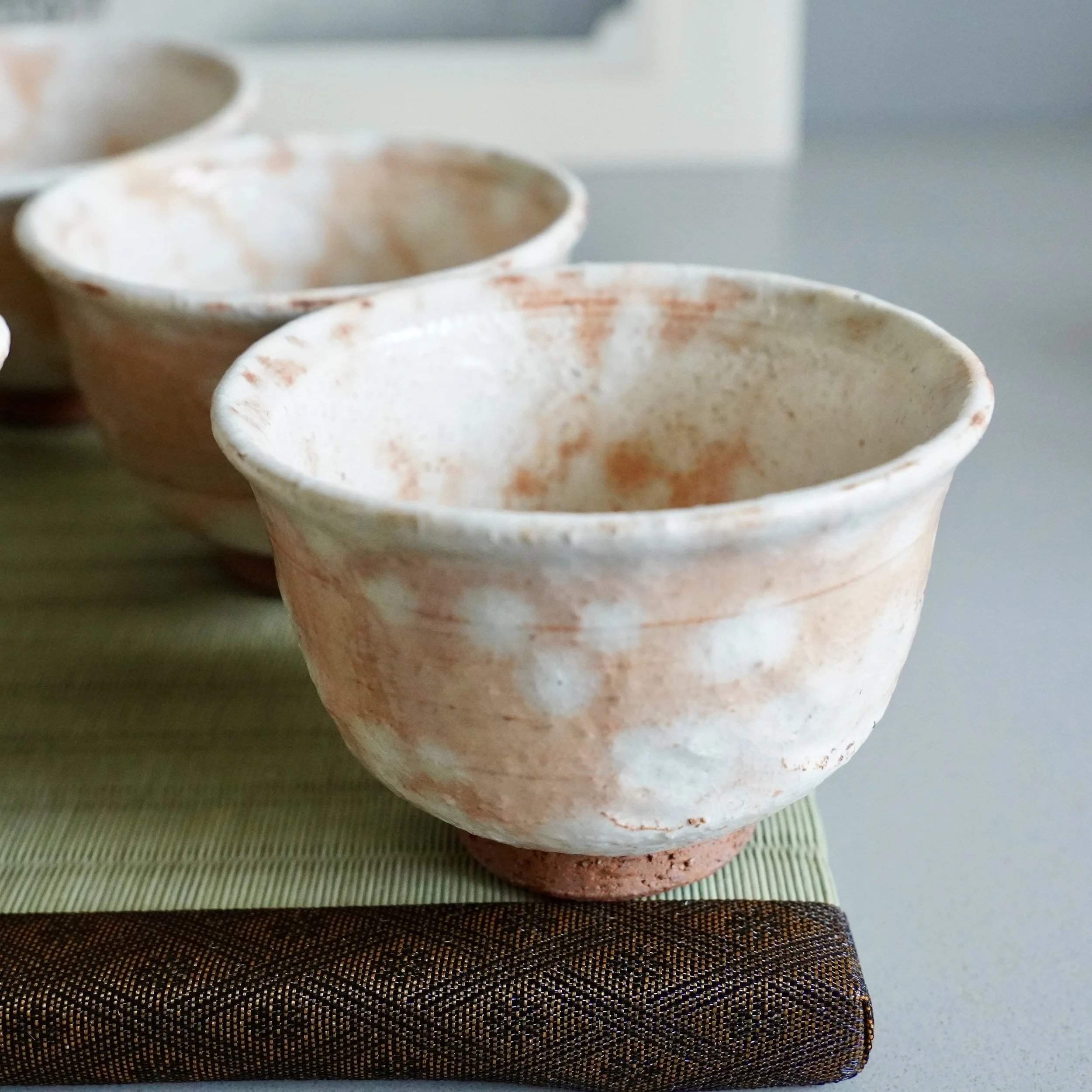 Shira-hagi Hagi-yaki yunomi by Taizan kiln, front view on wooden display, white rice straw ash glaze with russet cloud markings over terracotta clay, Japan Shōwa period