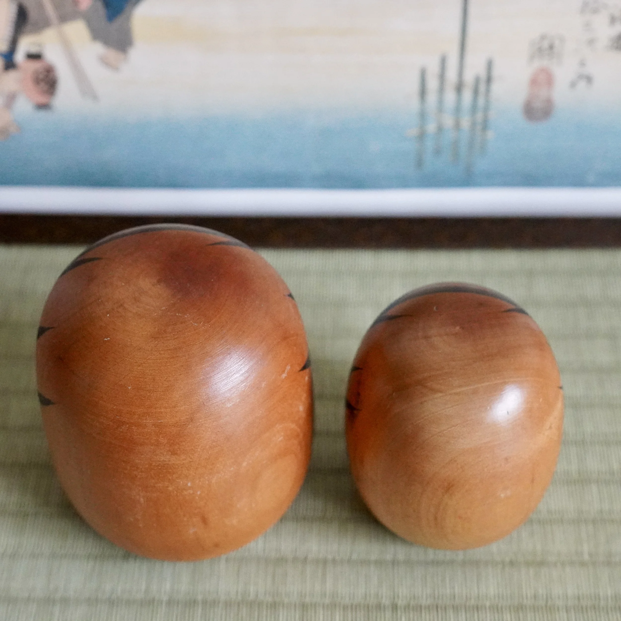 Close up of a vintage wooden daruma pair, bold black eyes and fuku kanji, Showa period folk art.