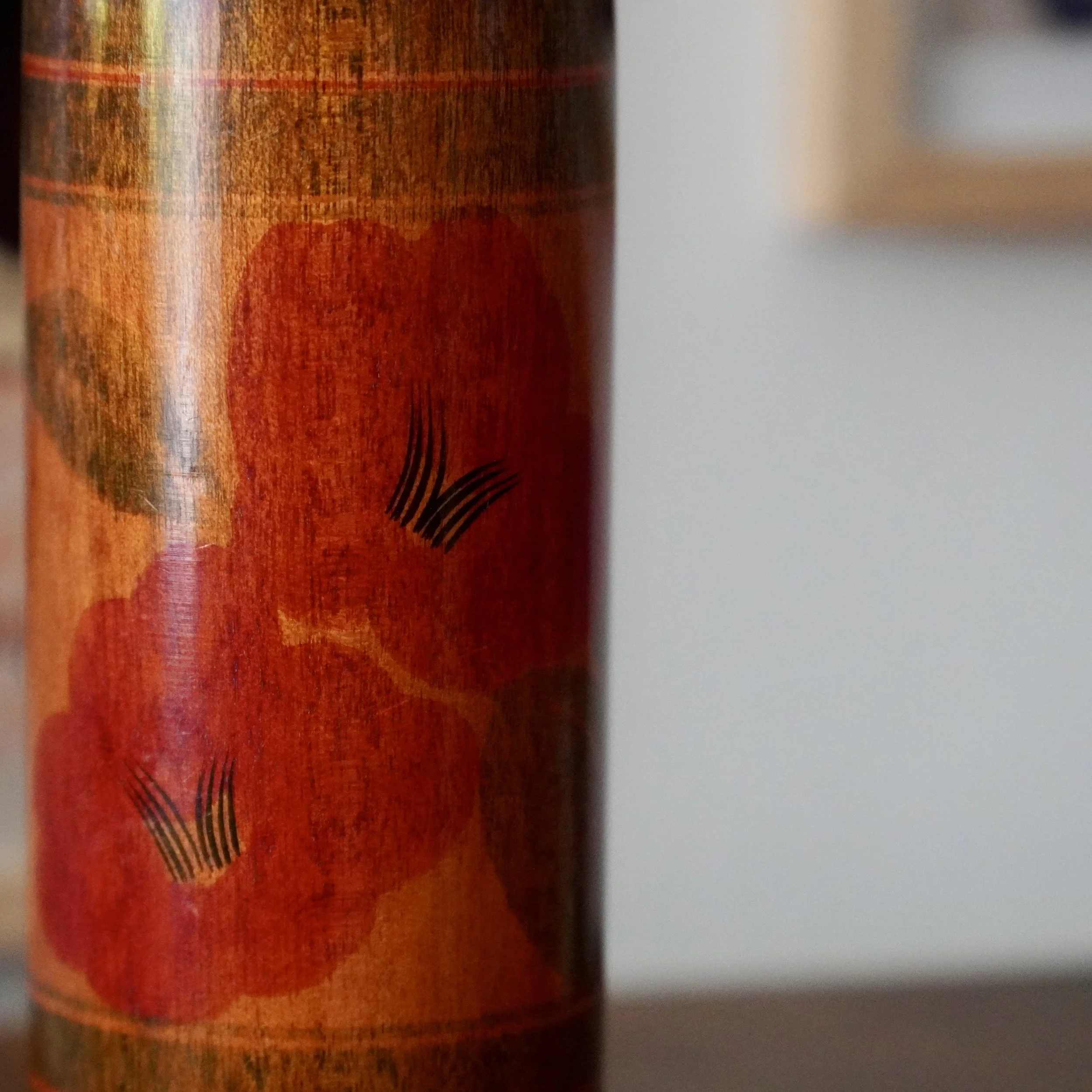 Close-up of red tsubaki flower painting on showa era noboru kokeshi doll