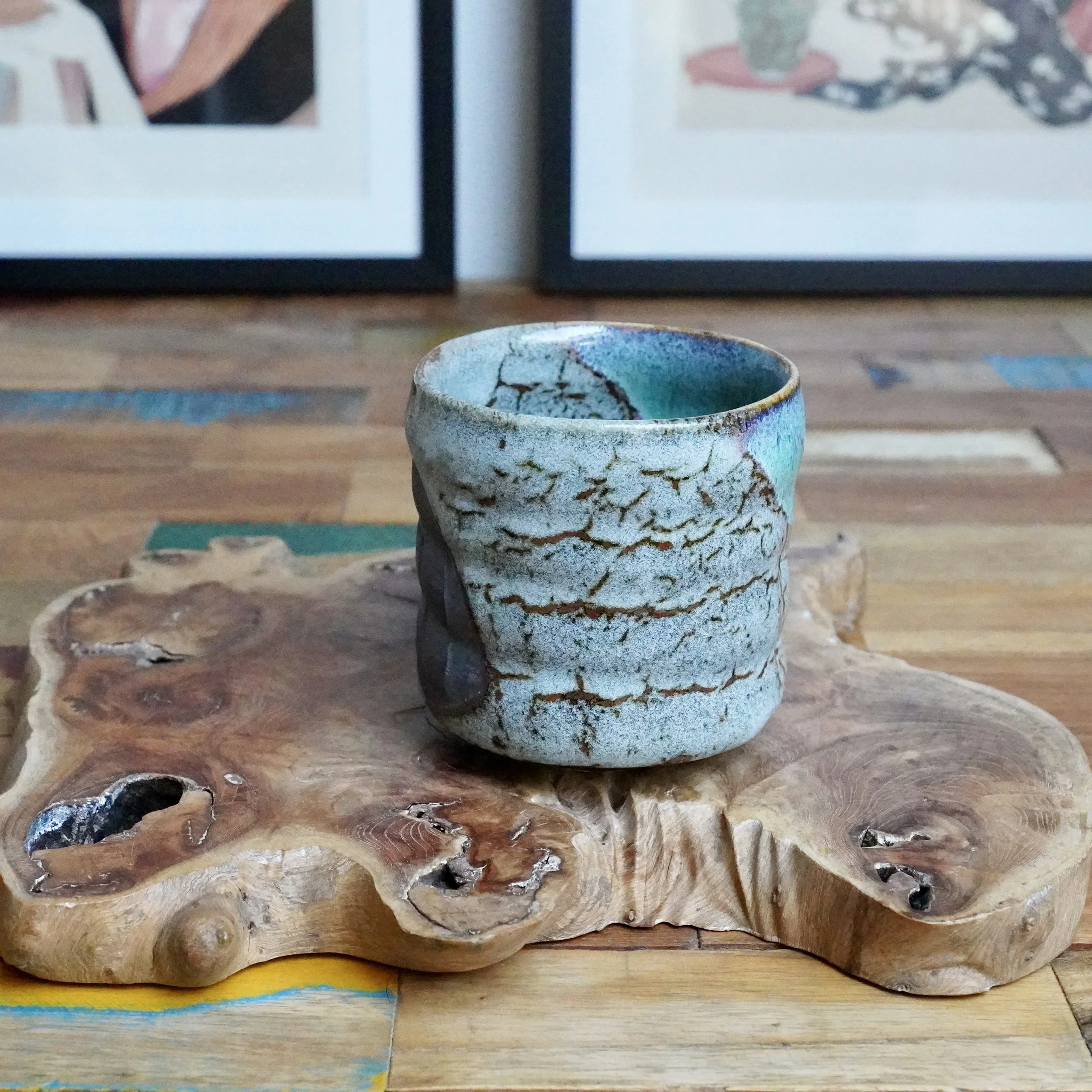 Hand-thrown tsutsu chawan, grey exterior with brown lines, pooling turquoise glaze at the rim, on a unique natural wood piece.