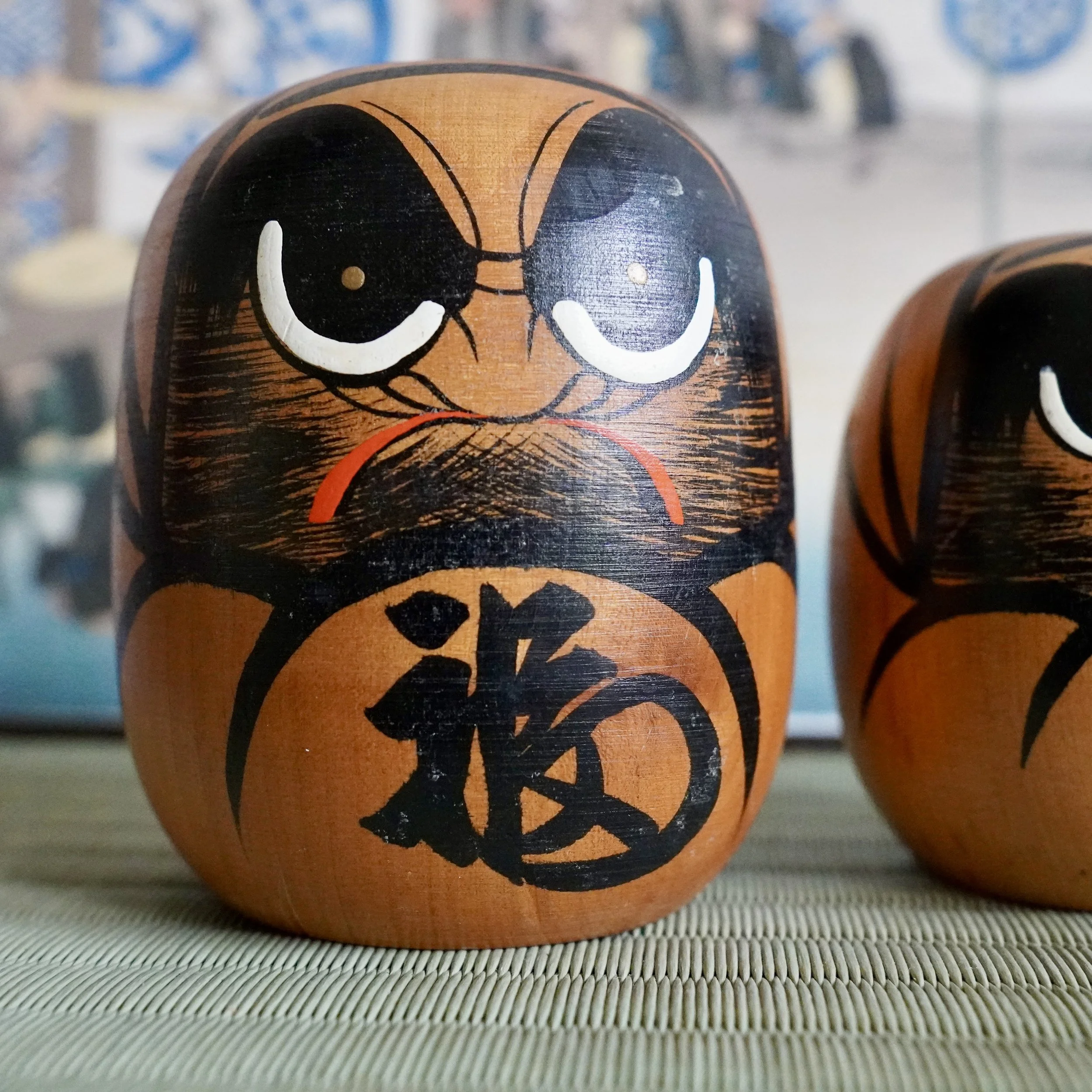Extreme close up of a hand painted daruma face, black eyebrow brushstroke detail, Showa period craft.