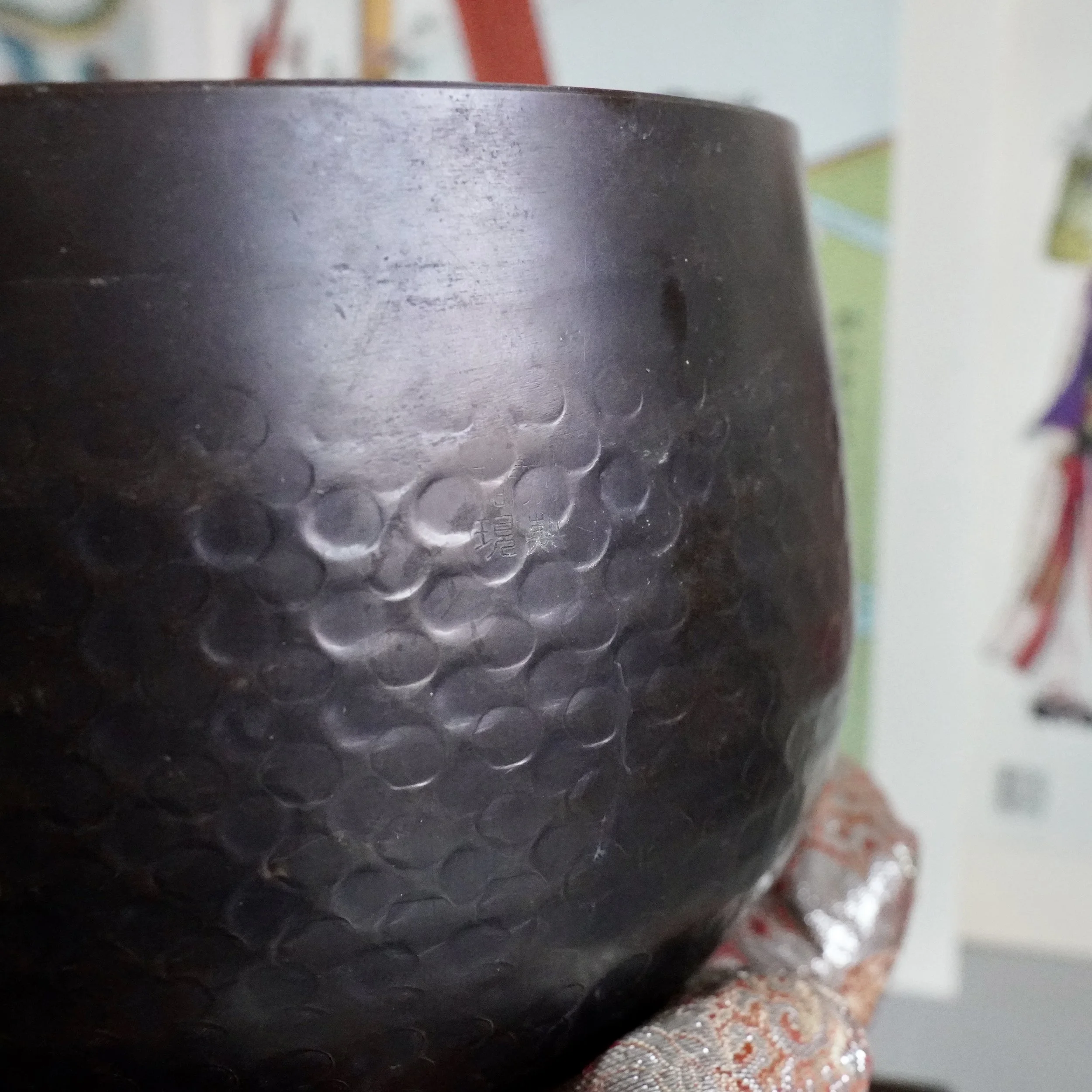 Close-up of hand-hammered dimpled texture on signed Tsutsumi orin, Japanese bronze singing bowl