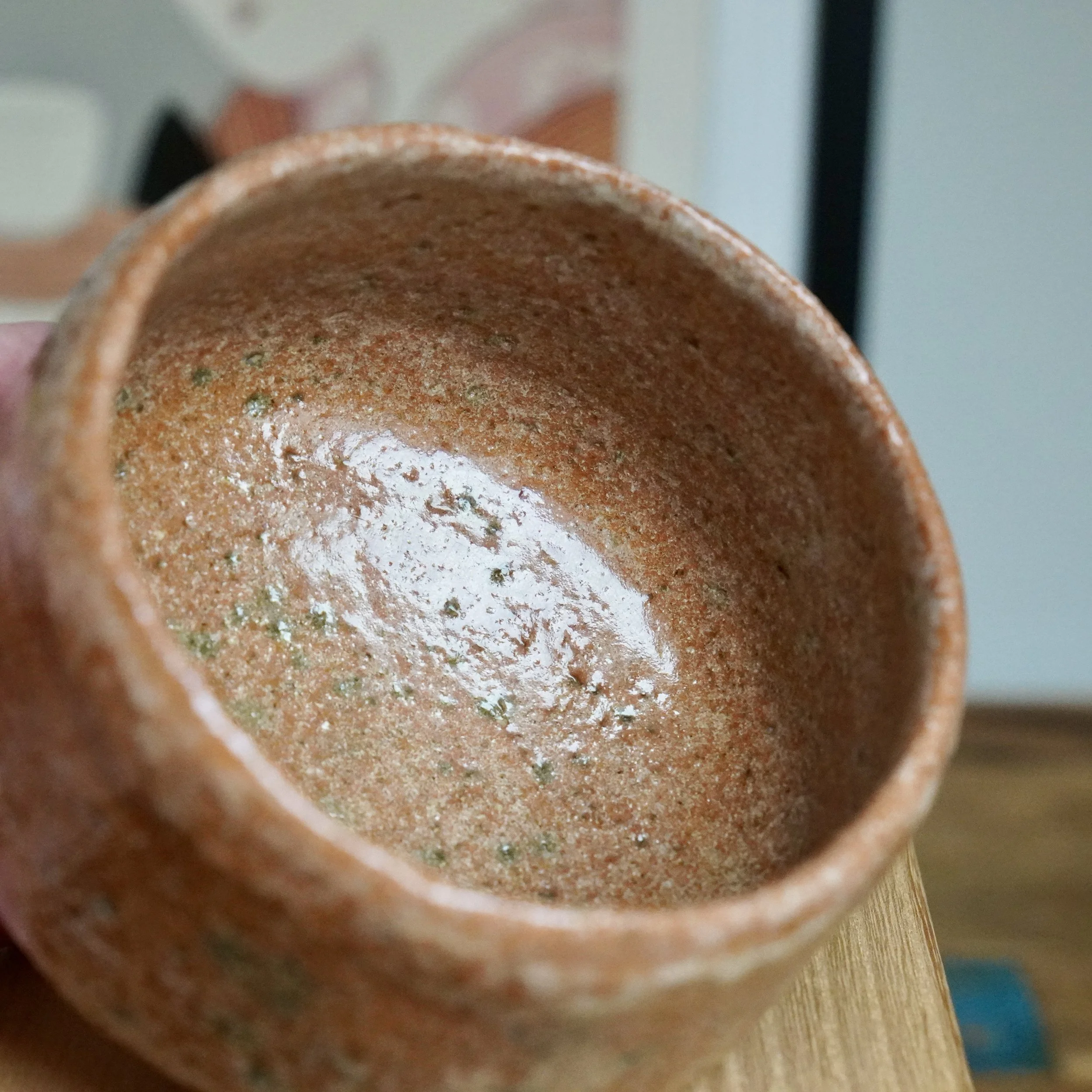 Sawada Hiroyuki's aka-raku chawan, interior view of its reddish-brown, sandy and pitted surface with green specks and glossy glaze.