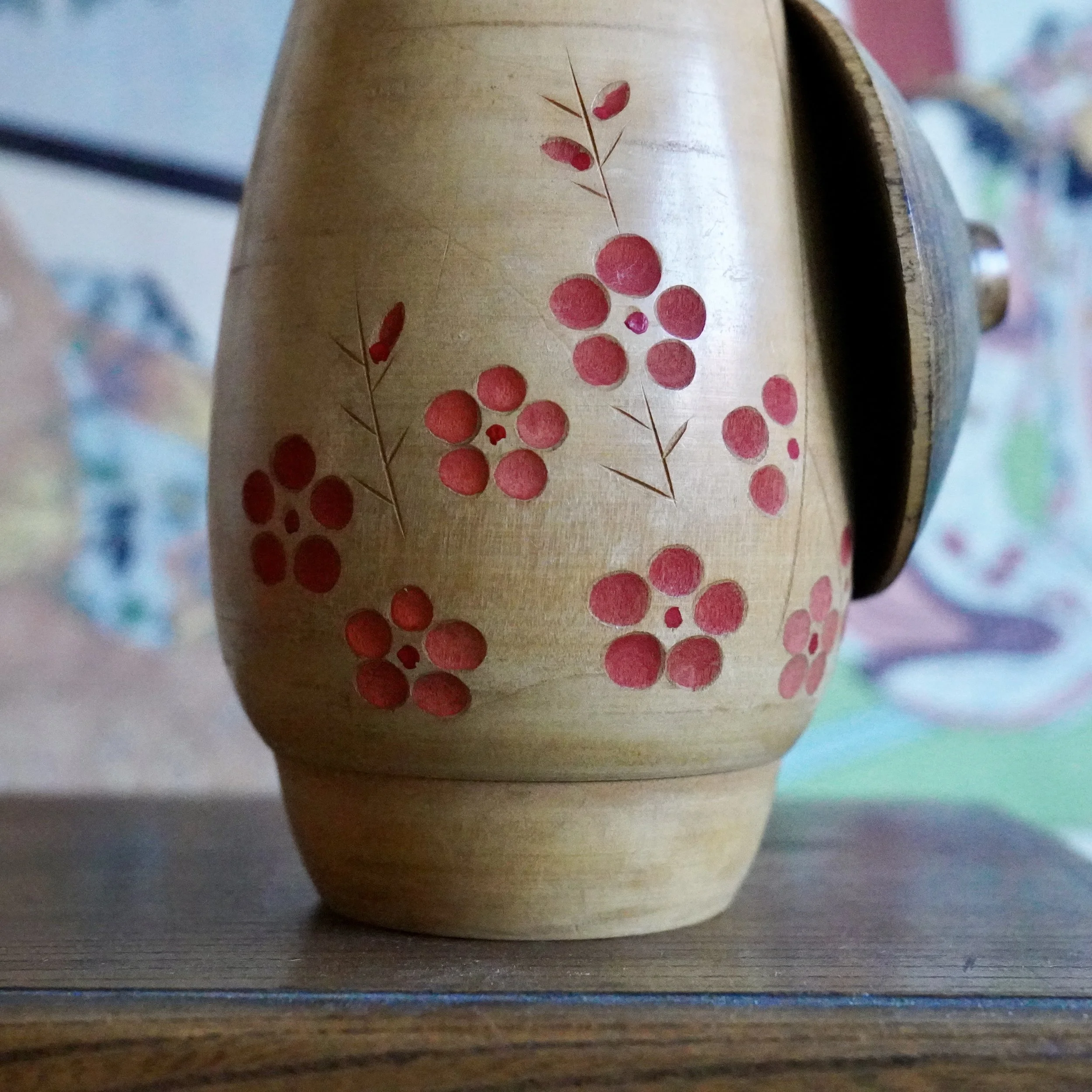 Close up of carved plum blossom motif filled with red pigment on Sato Suigai sōsaku kokeshi
