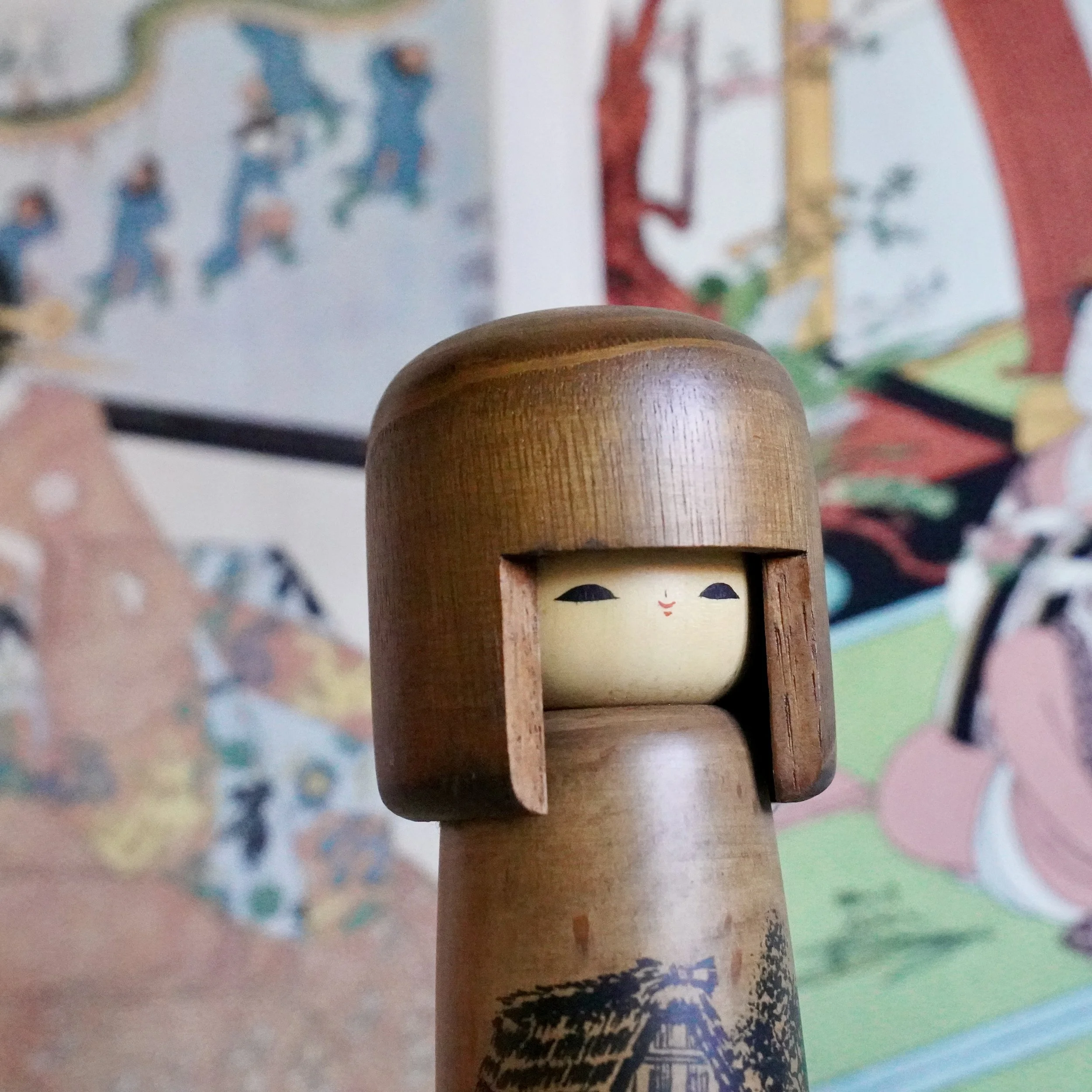 Usaburō kokeshi doll face close up, painted eyes under dark wooden hair panels