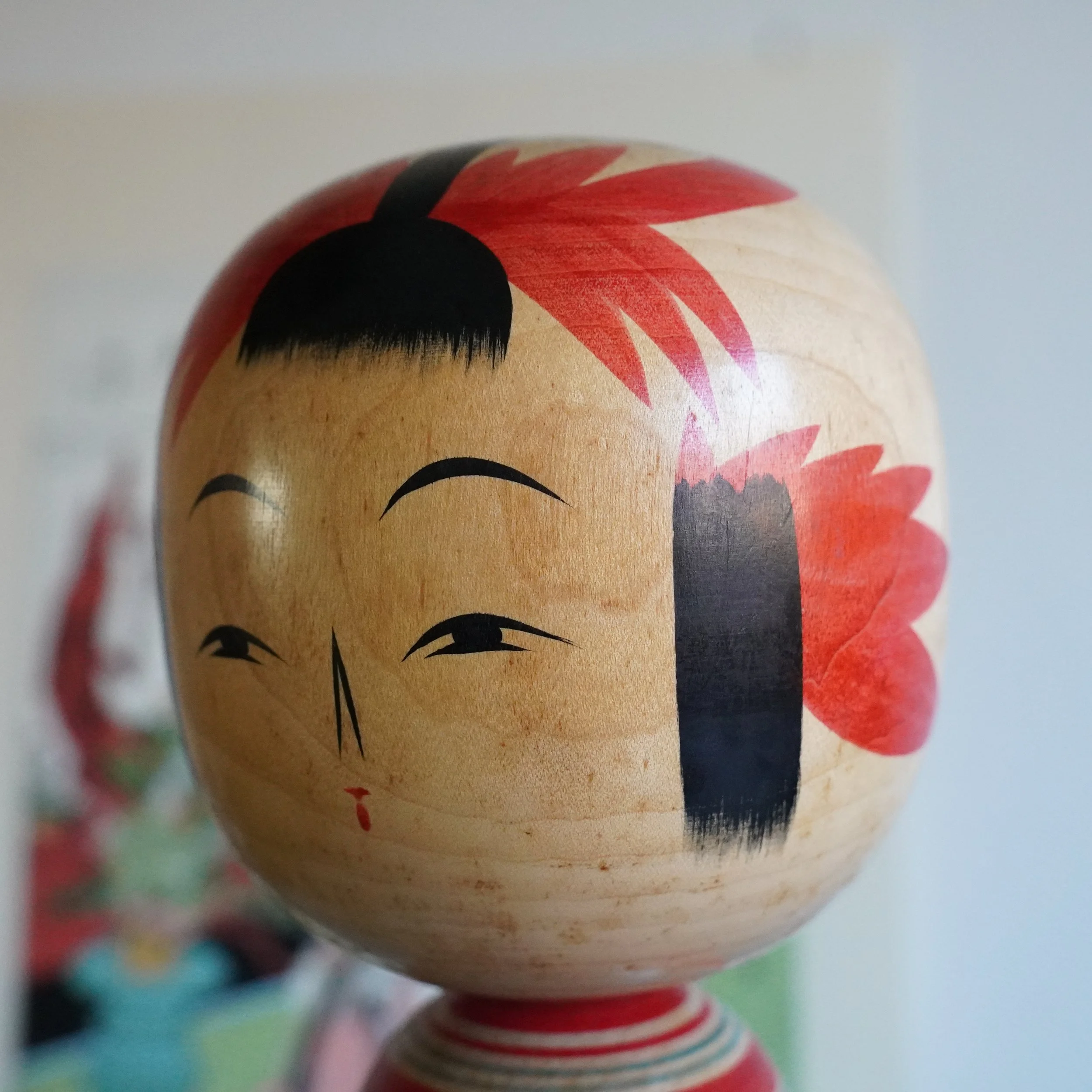 Close view of Yamagata kokeshi face and painted hair decoration, Takasaki Eiichirō, gentle hand-painted expression with red floral crown motif, Shōwa period