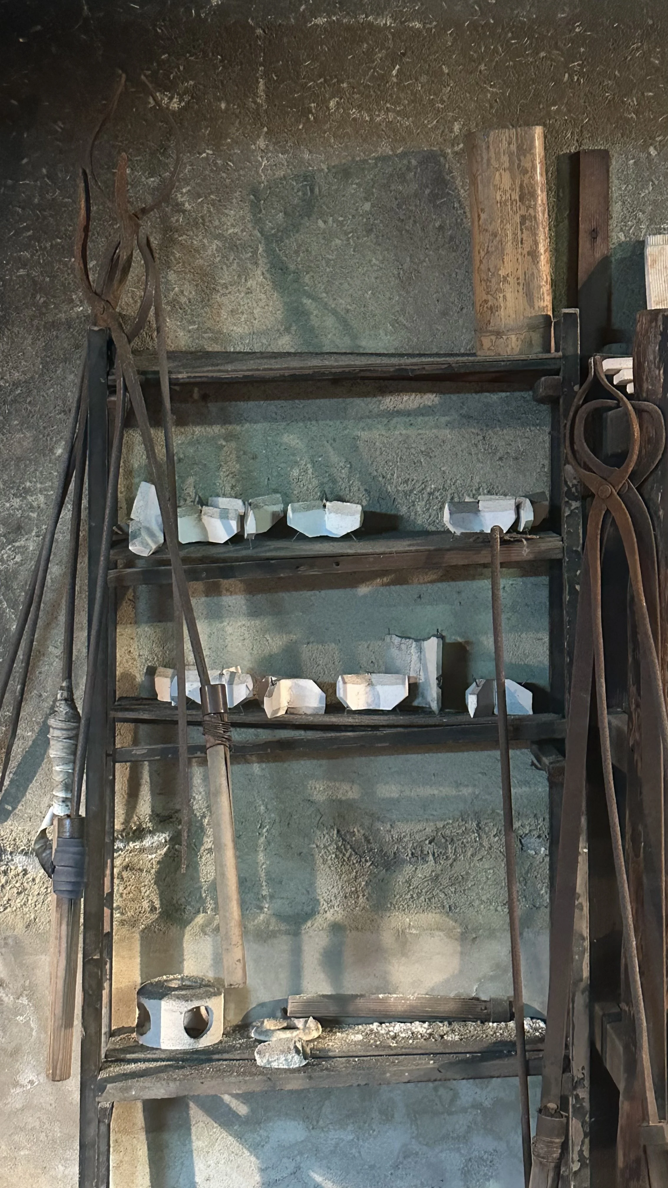 Workshop shelves at Raku Studio Waraku in Gion, Kyoto, holding ceramic pieces at every stage of production from raw clay to finished glaze, Raku ware atelier