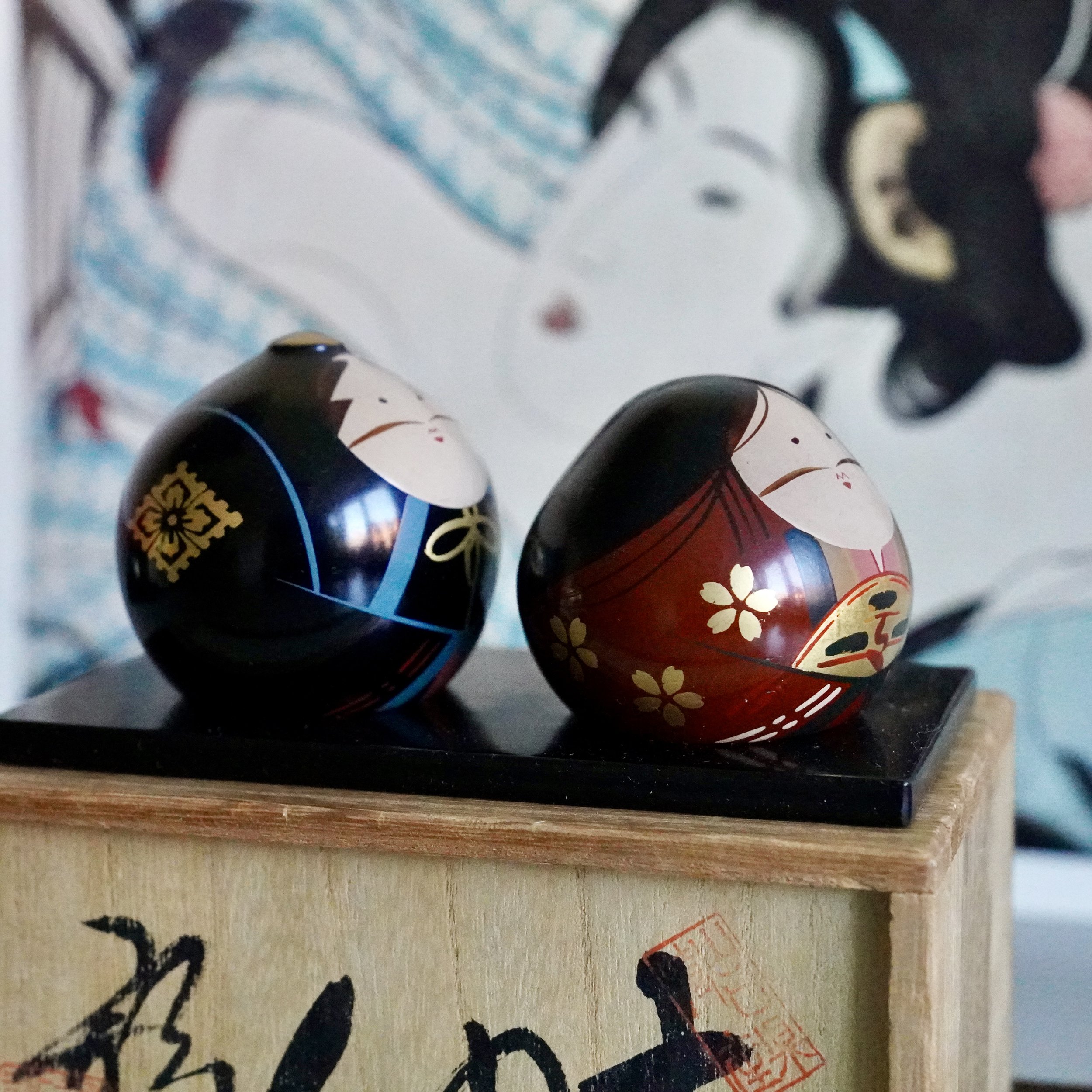 Ouchi-nuri bride and groom dolls on black lacquered stand beside original tomobako