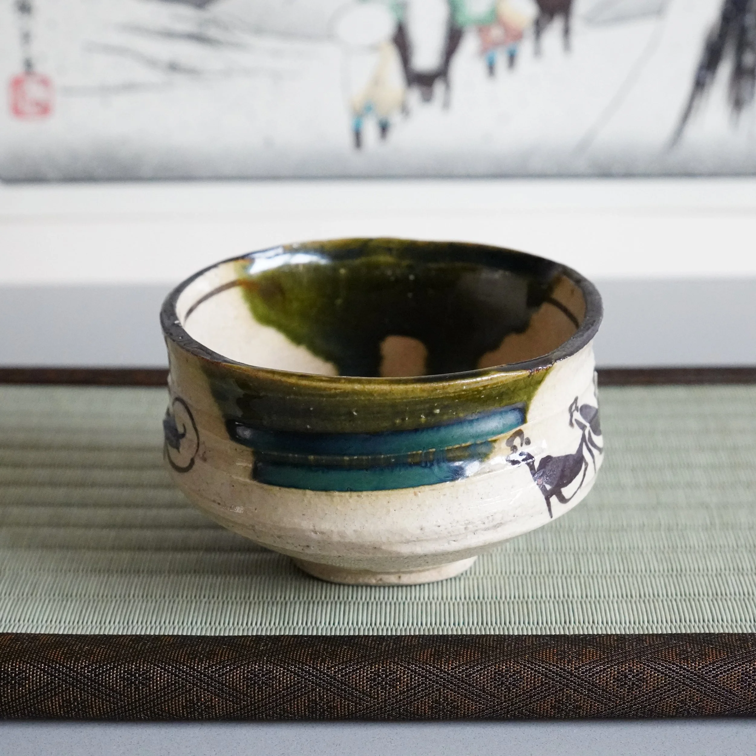 Ao-Oribe chawan interior overhead view copper green glaze deepening to teal where pooled thickest vintage bamboo chasen matcha whisk resting inside Mino ware Japanese stoneware tea bowl