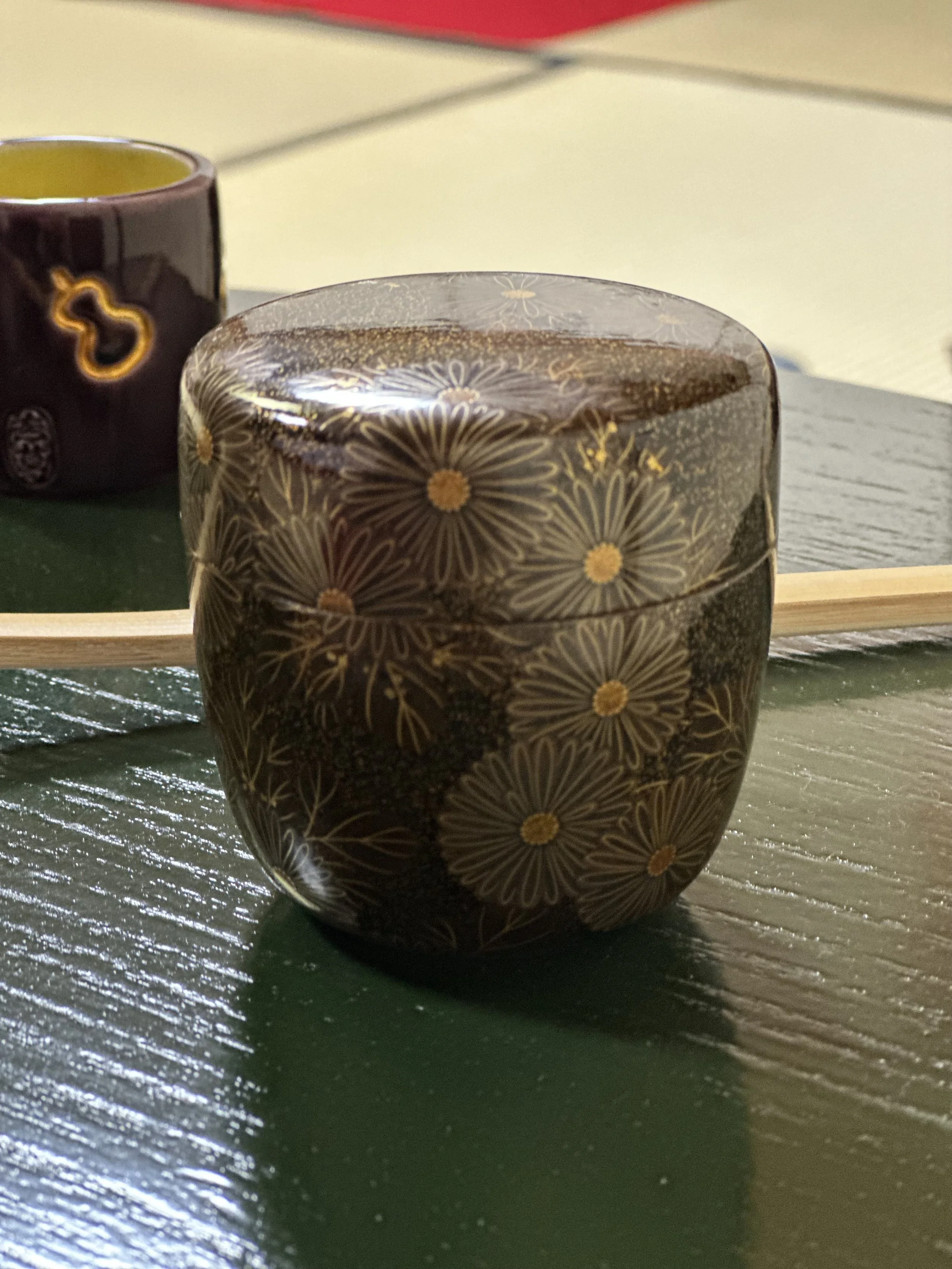 Dark lacquered natsume matcha caddy with gold chrysanthemum pattern, Japanese tea ceremony