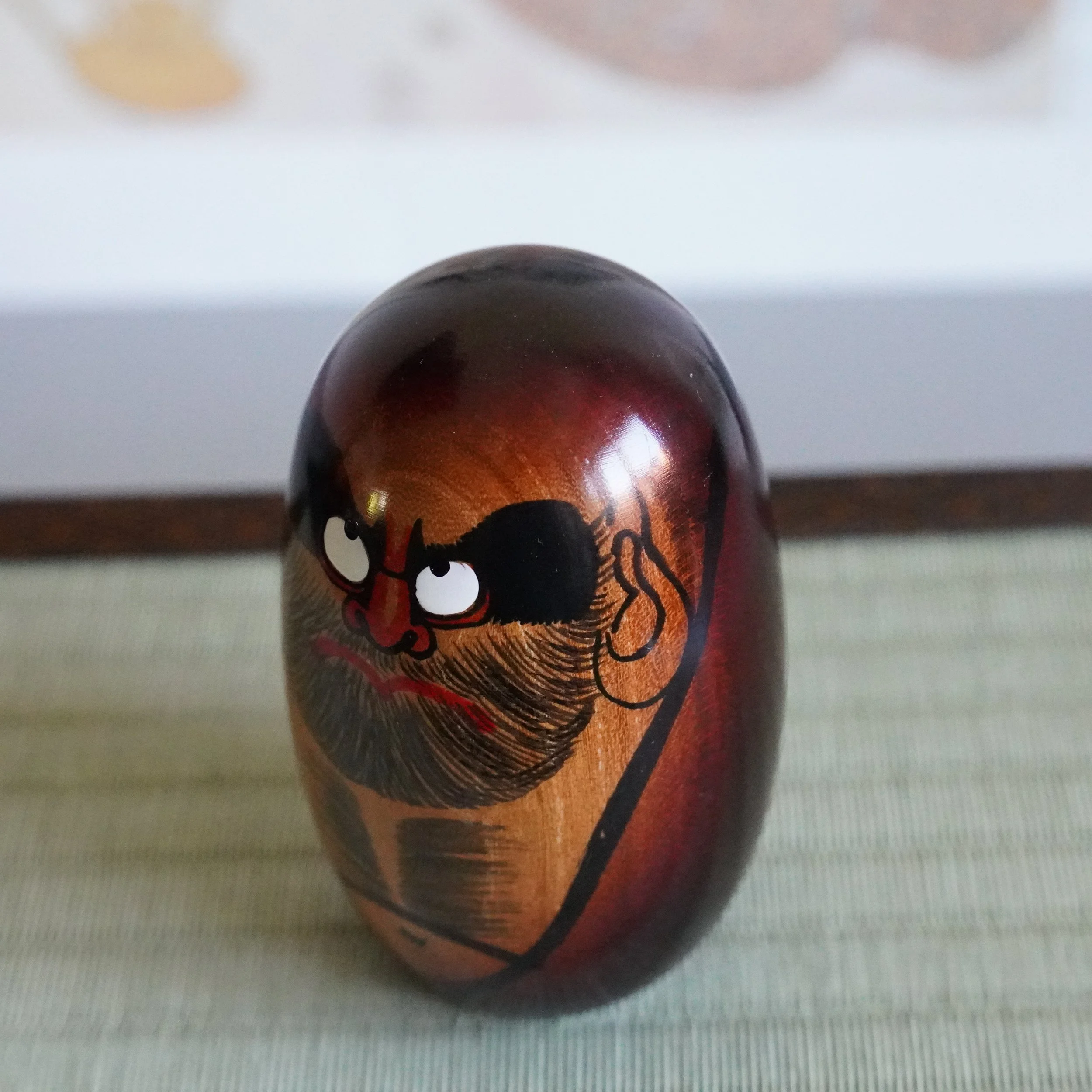 Close angled view of a hand painted Daruma Daishi face by Seifu Gono, keyaki wood