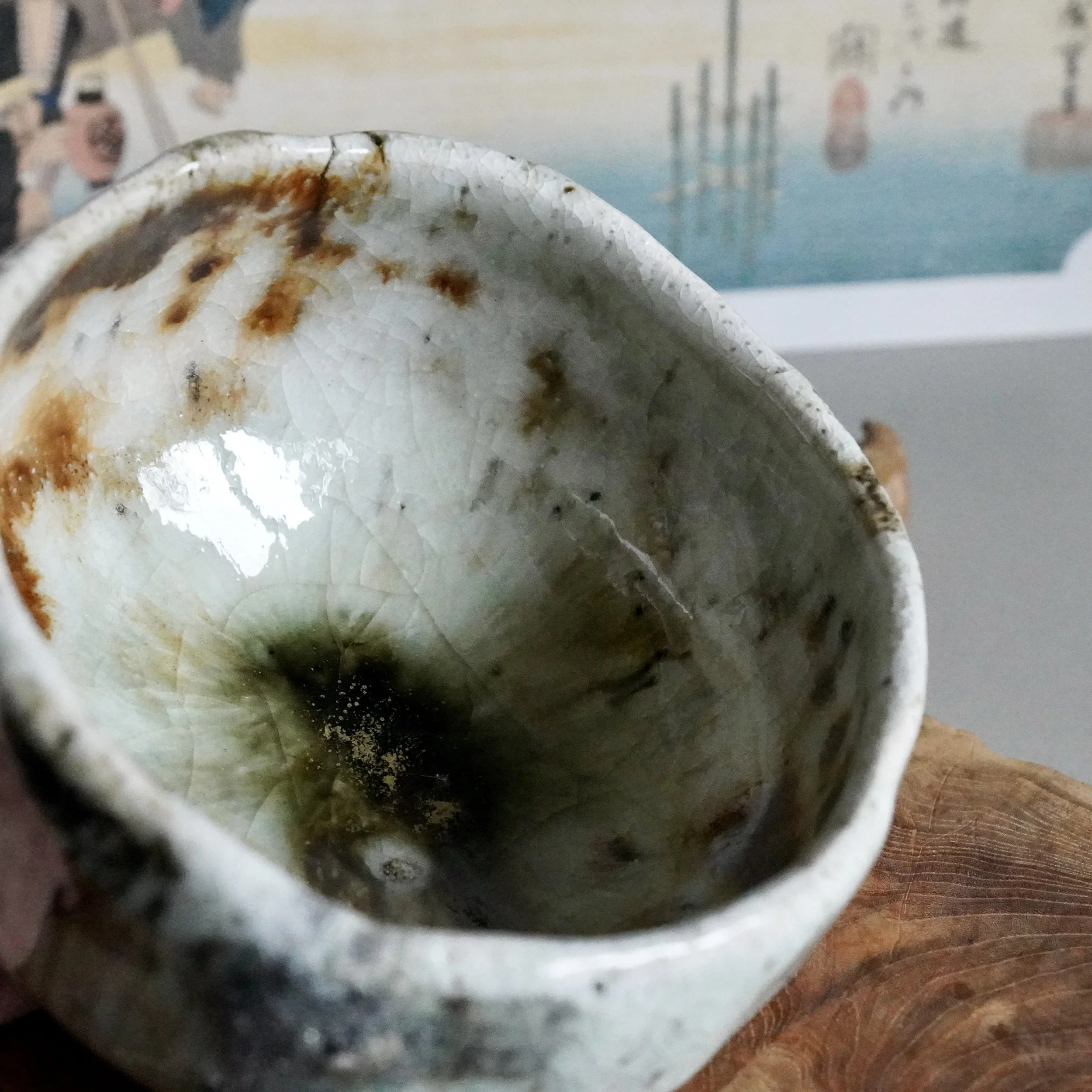 Deguchi Eiji wood-fired chawan, crackled white and rust-brown glaze on the exterior, pooling into mossy green and dark with golden specks inside.