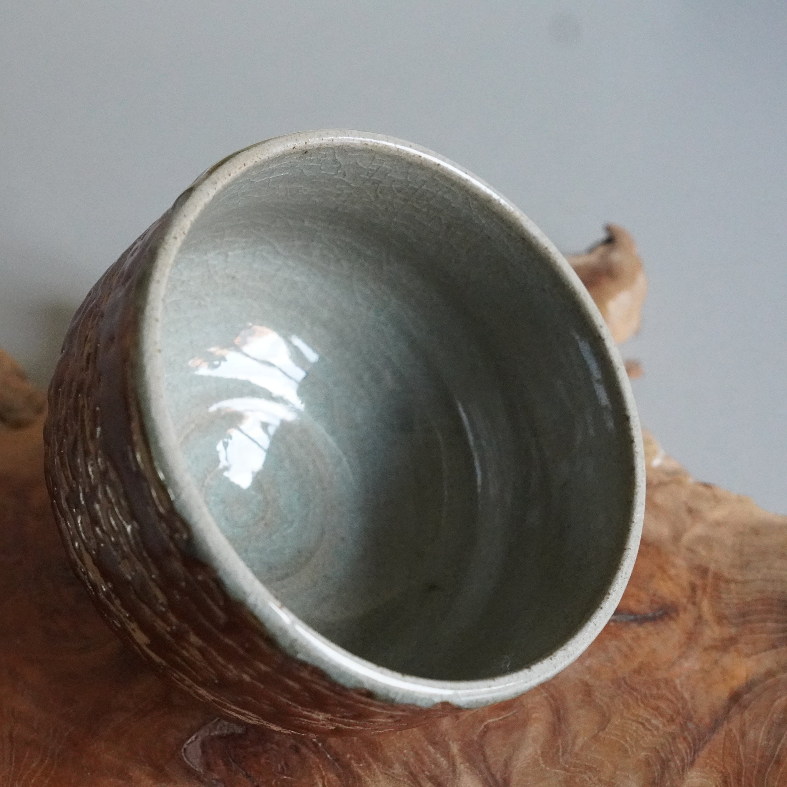 Inuyama-yaki matsukawa chawan tilted on side, showing interior glaze and exterior bark texture
