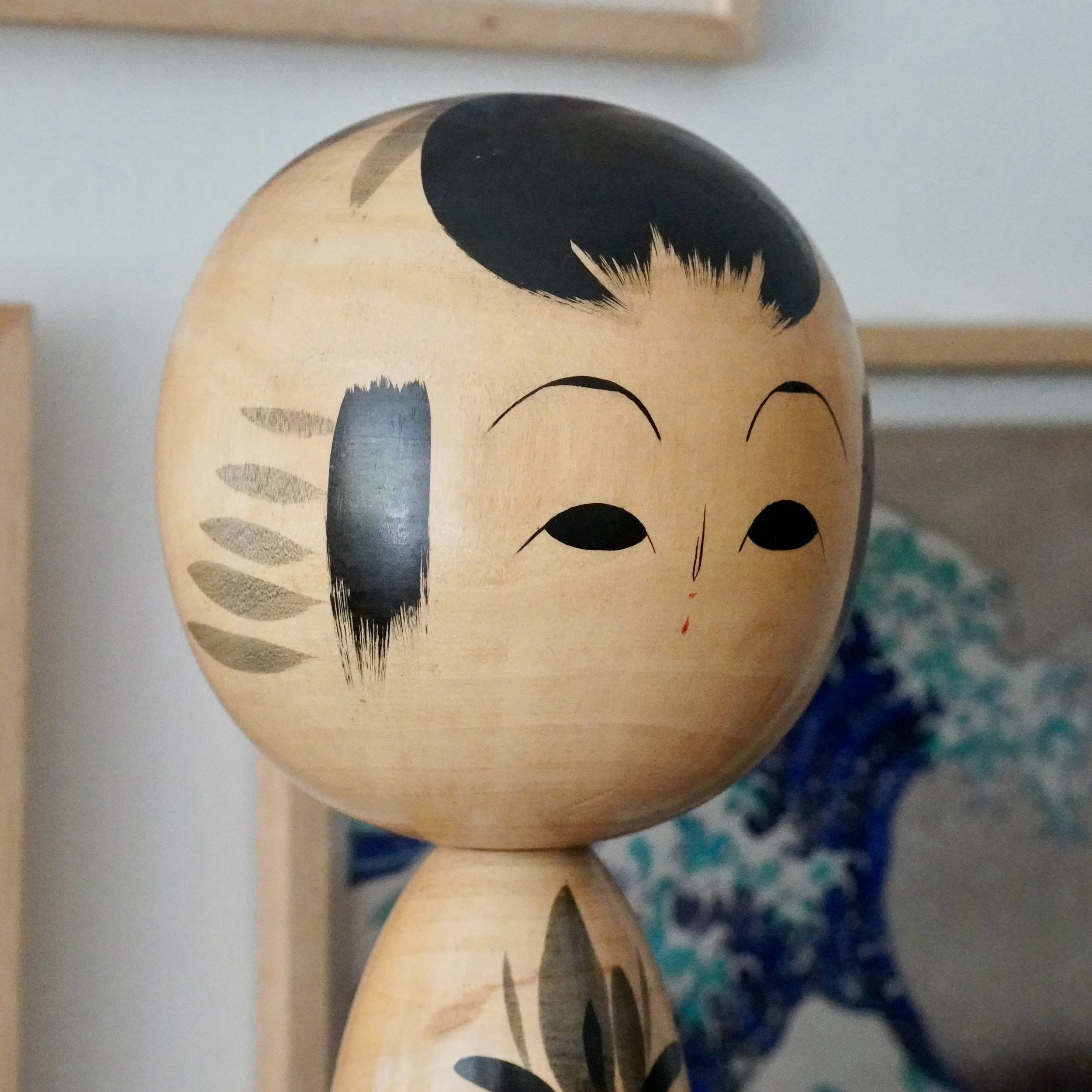 Japanese kokeshi doll face close-up, hand-painted eyes and eyebrows, dry-brushed grey hair accent, Showa period