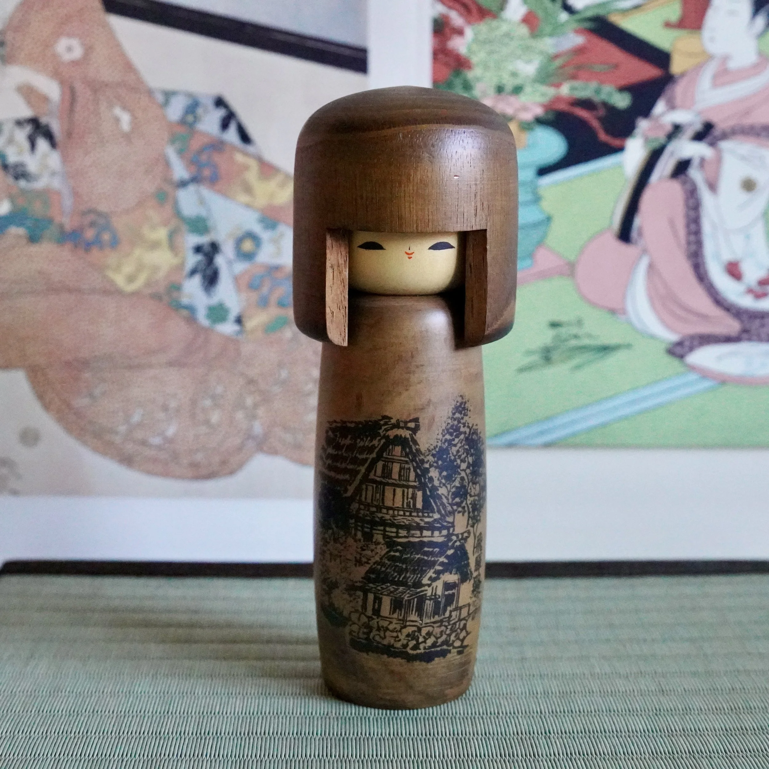 Sōsaku kokeshi doll by Usaburō with painted face and Hida road farmhouse scene