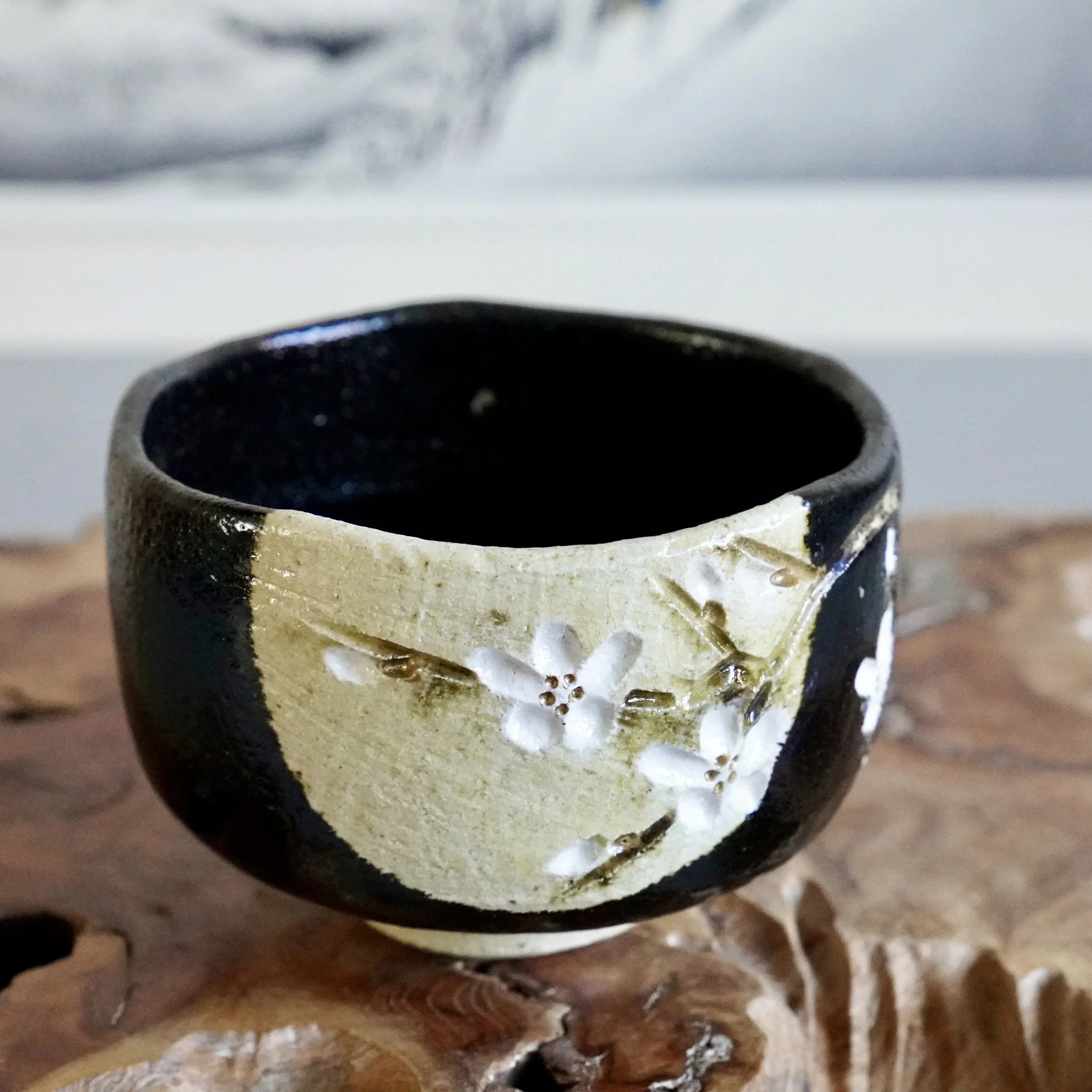Front view of kuro chawan with carved cherry blossom branches