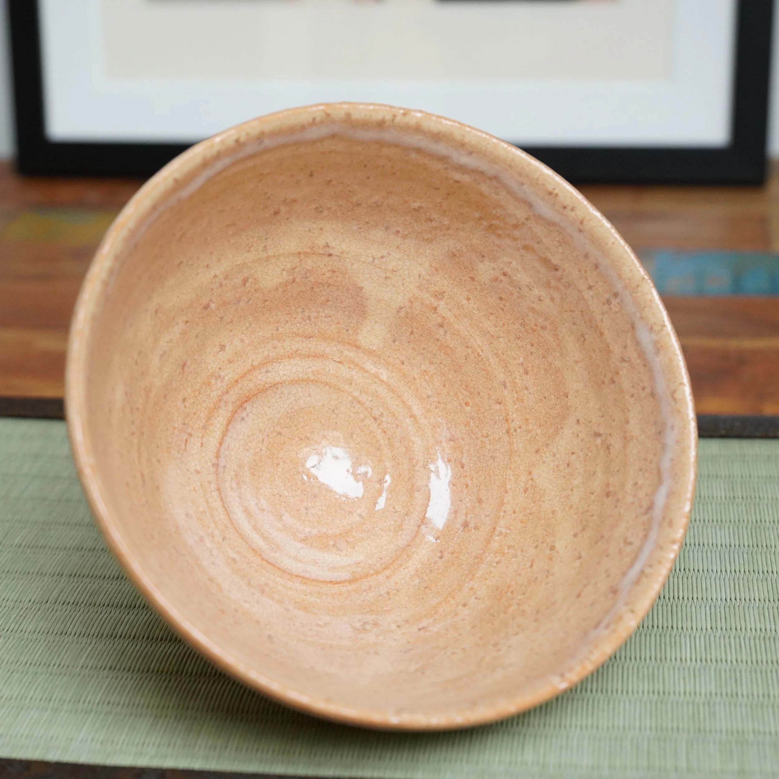 Interior view of a Hagi-yaki chawan by Kaneko Nobuhiko. Its salmon pink surface has a crackle glaze, dark flecks, and visible wheel marks, with a milky white rim.