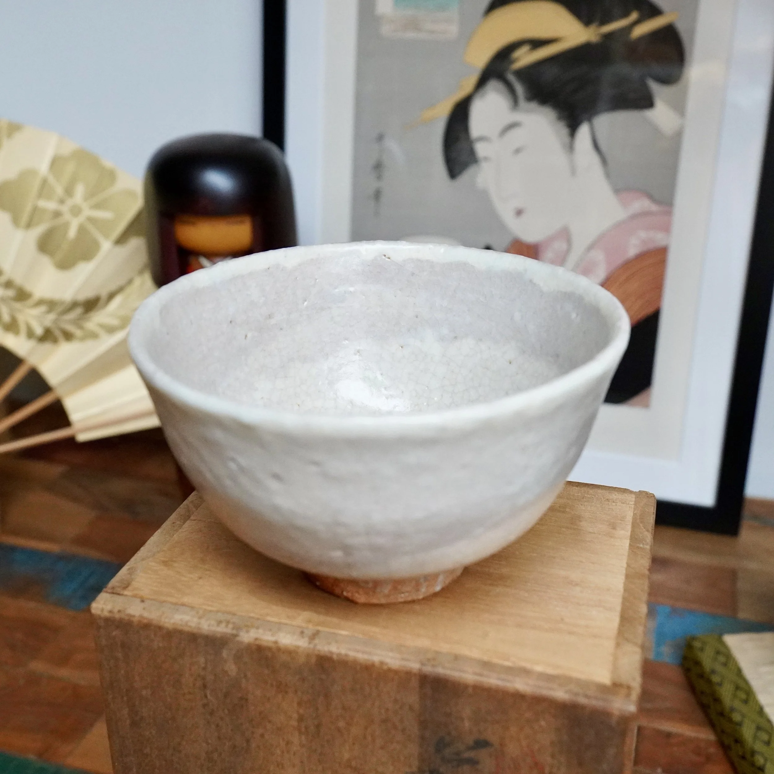 Hagi-yaki chawan by Tamamura Shōgetsu, 1972, white crackled glaze with tea stains and reddish clay foot, on a wooden box.