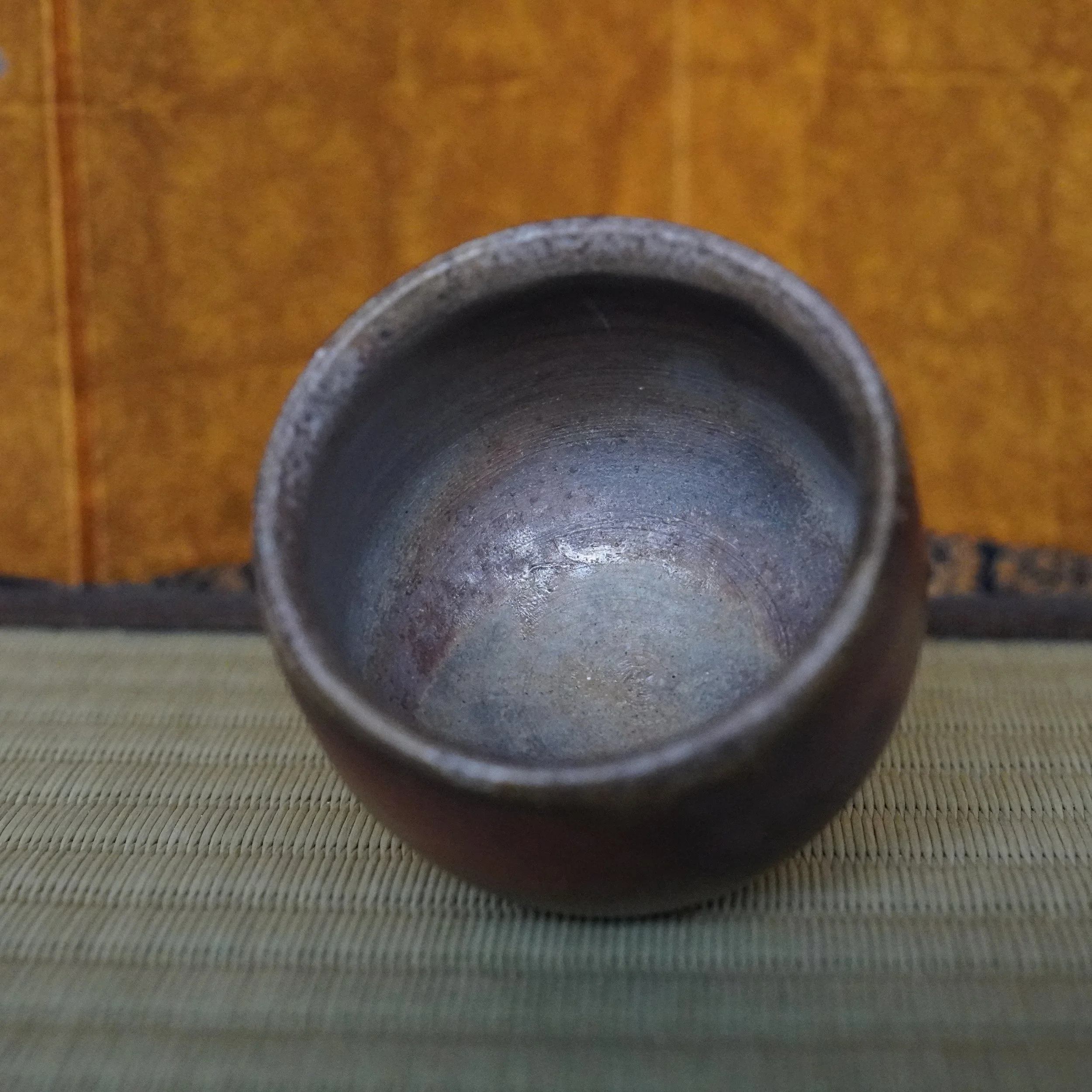 Yamamoto Sōshū Bizen-yaki guinomi, angled top view of the unglazed, dark clay cup with a mottled grey-blue hidasuki interior and throwing lines.
