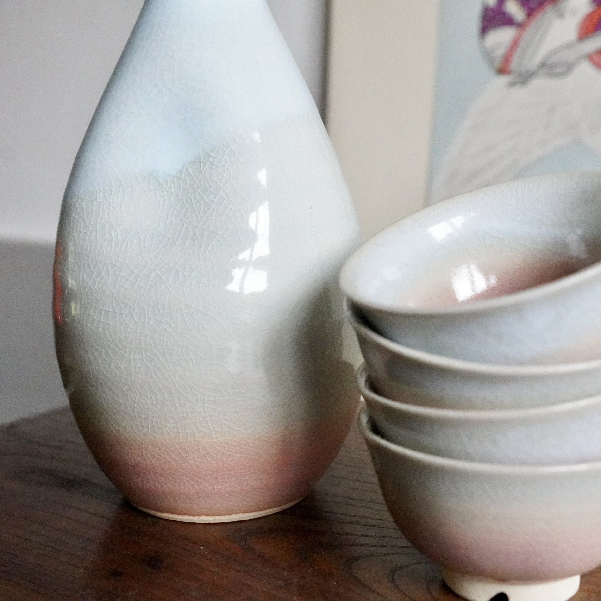 Hagi-yaki sake set: a tokkuri and stacked ochoko display a blush-to-pale blue-grey gradient glaze with fine crazing.