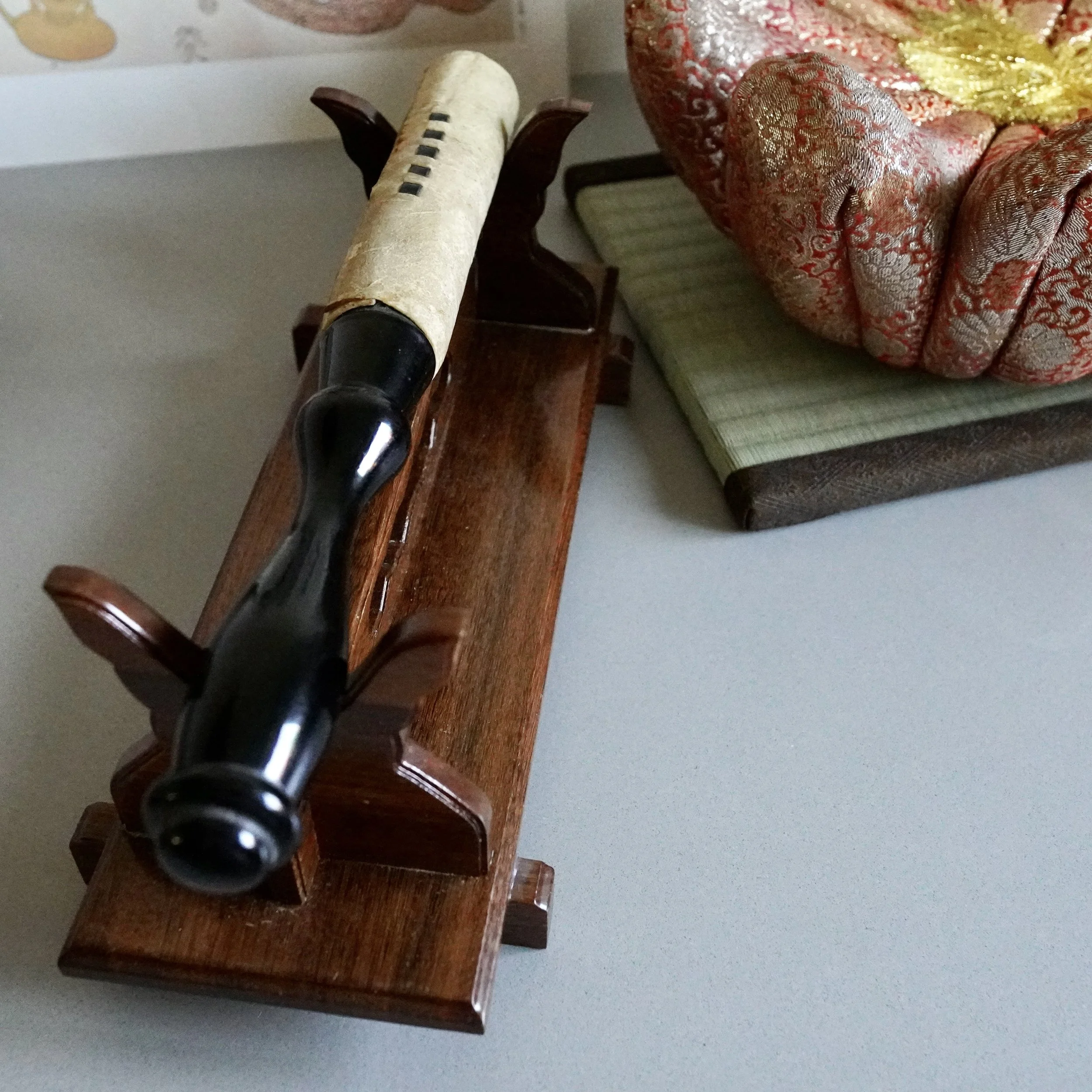 Close-up of black lacquered striker resting on wooden stand for Japanese orin singing bowl