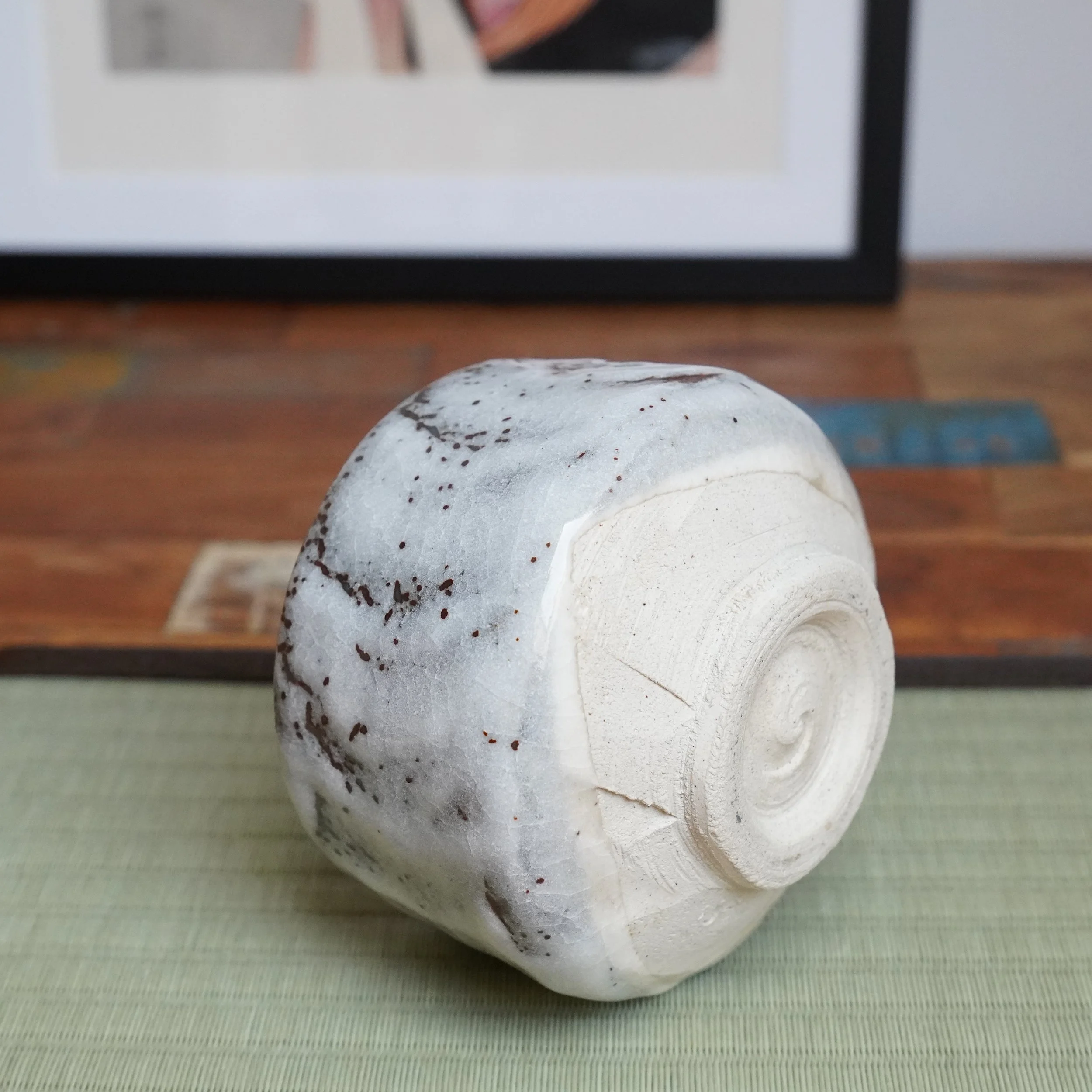 Katō Shōzan's oni-Shino chawan lying on its side, showing its white speckled glaze and textured unglazed foot.