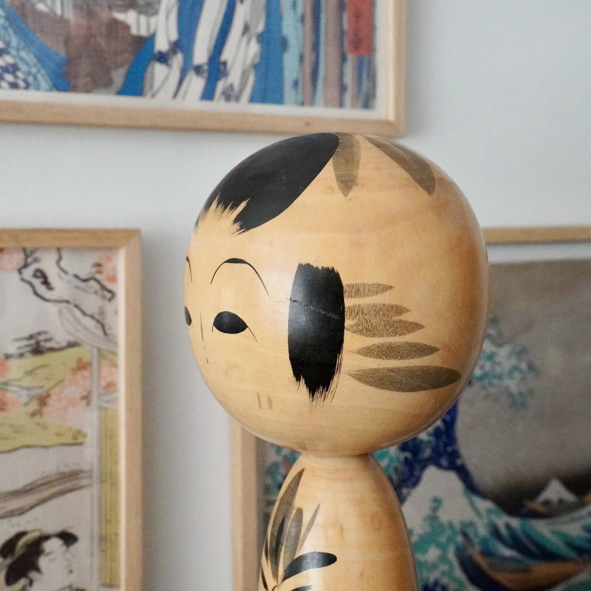 Kokeshi doll face three-quarter angle, black bowl-cut hair, dry-brushed hair accent made by nidaime tetsuen