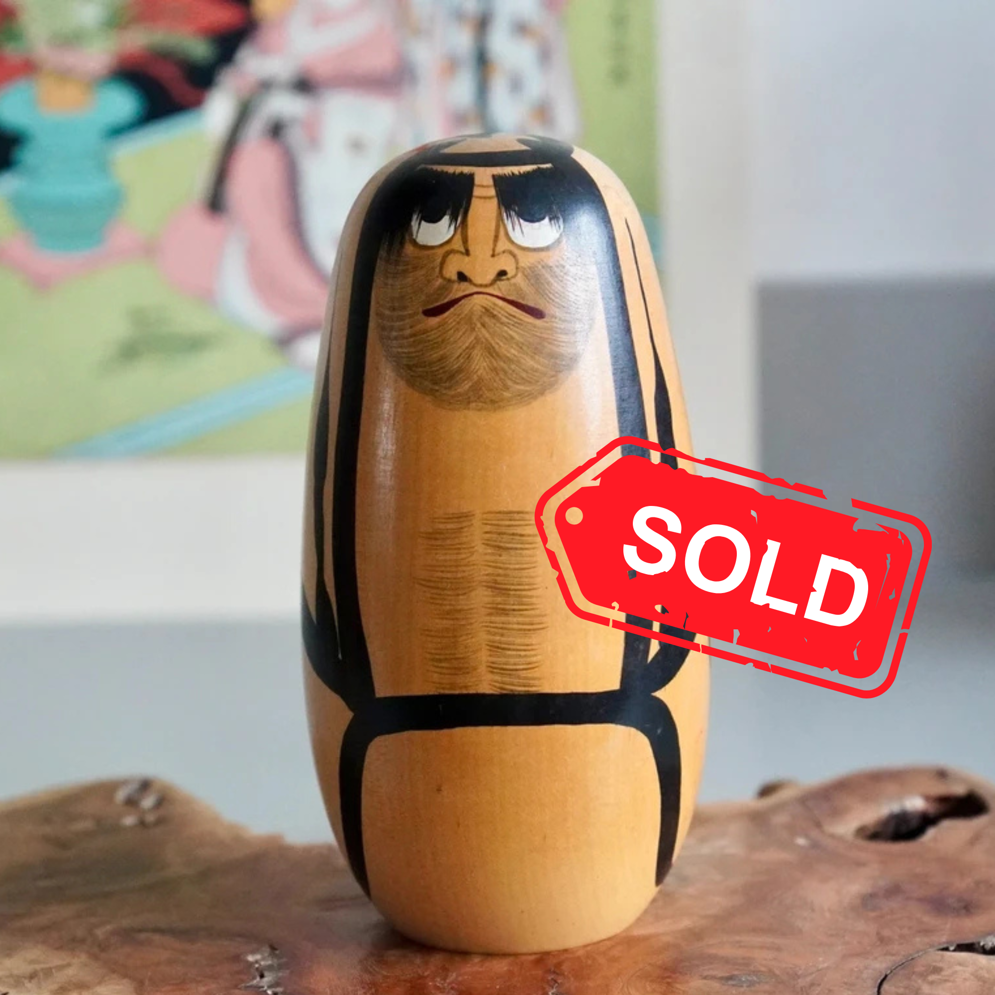 Nanten daruma, turned wood with hand-painted decoration, Shōwa period, displayed on wooden plank with ukiyoe print in background